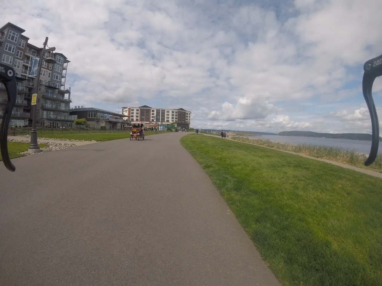Paved path by water, people cycling and walking under cloudy sky. - Ruston Way Trail – Owen Beach loop from University of Puget Sound