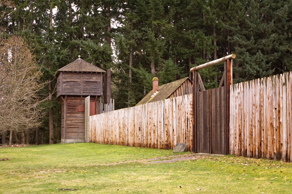 Wooden fort with watchtower and palisade fence, surrounded by trees. - Point Defiance and Ruston Way Loop