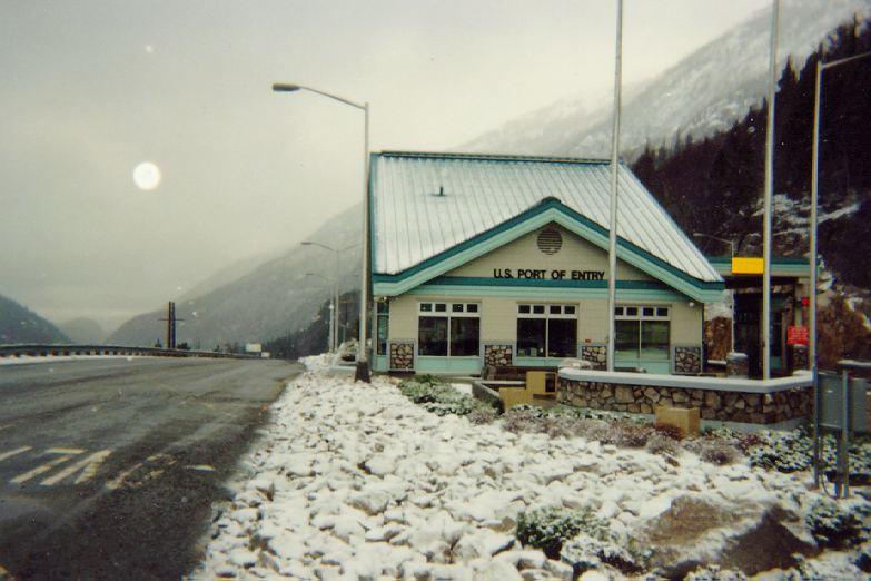 Snow-covered building labeled "U.S. Port of Entry" next to a road.