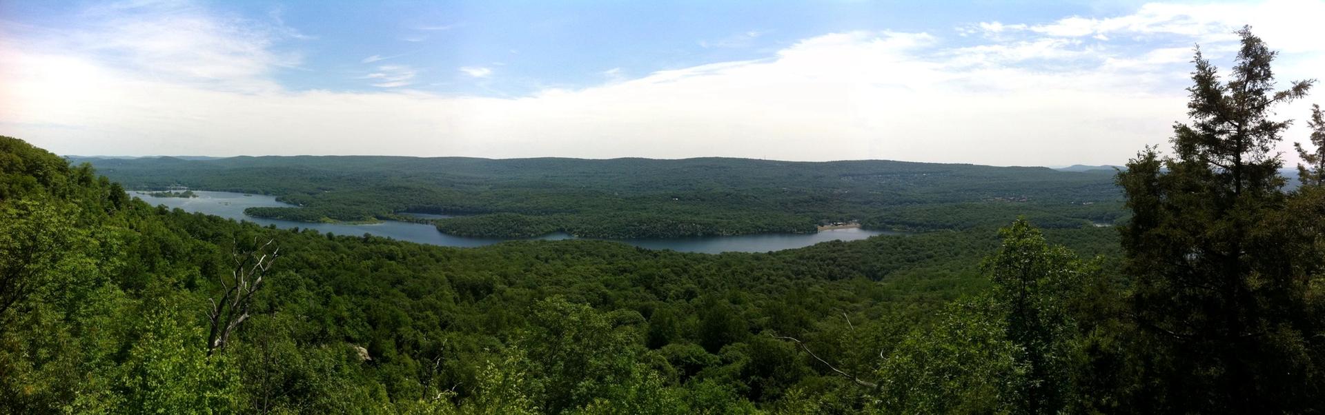Panoramic view of a vast green forest with several lakes under a cloudy sky.