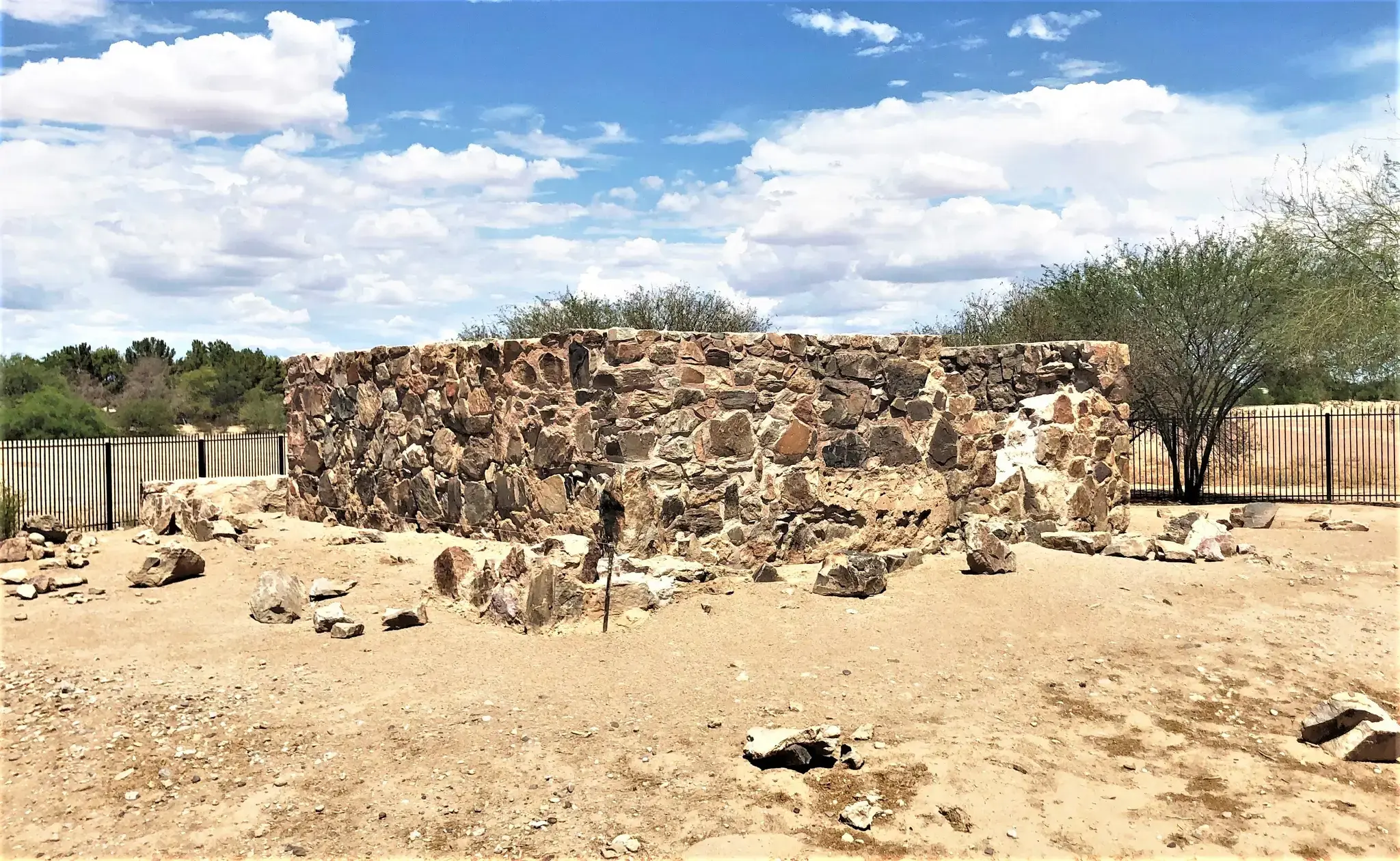 Stone ruins on dry ground under a bright, cloudy sky.