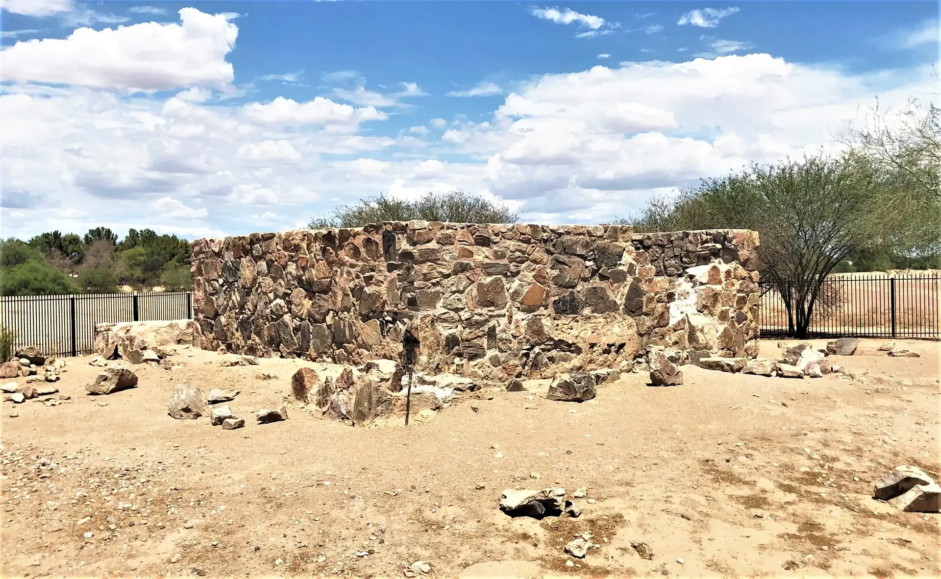 Stone ruins on dry ground under a bright, cloudy sky.
