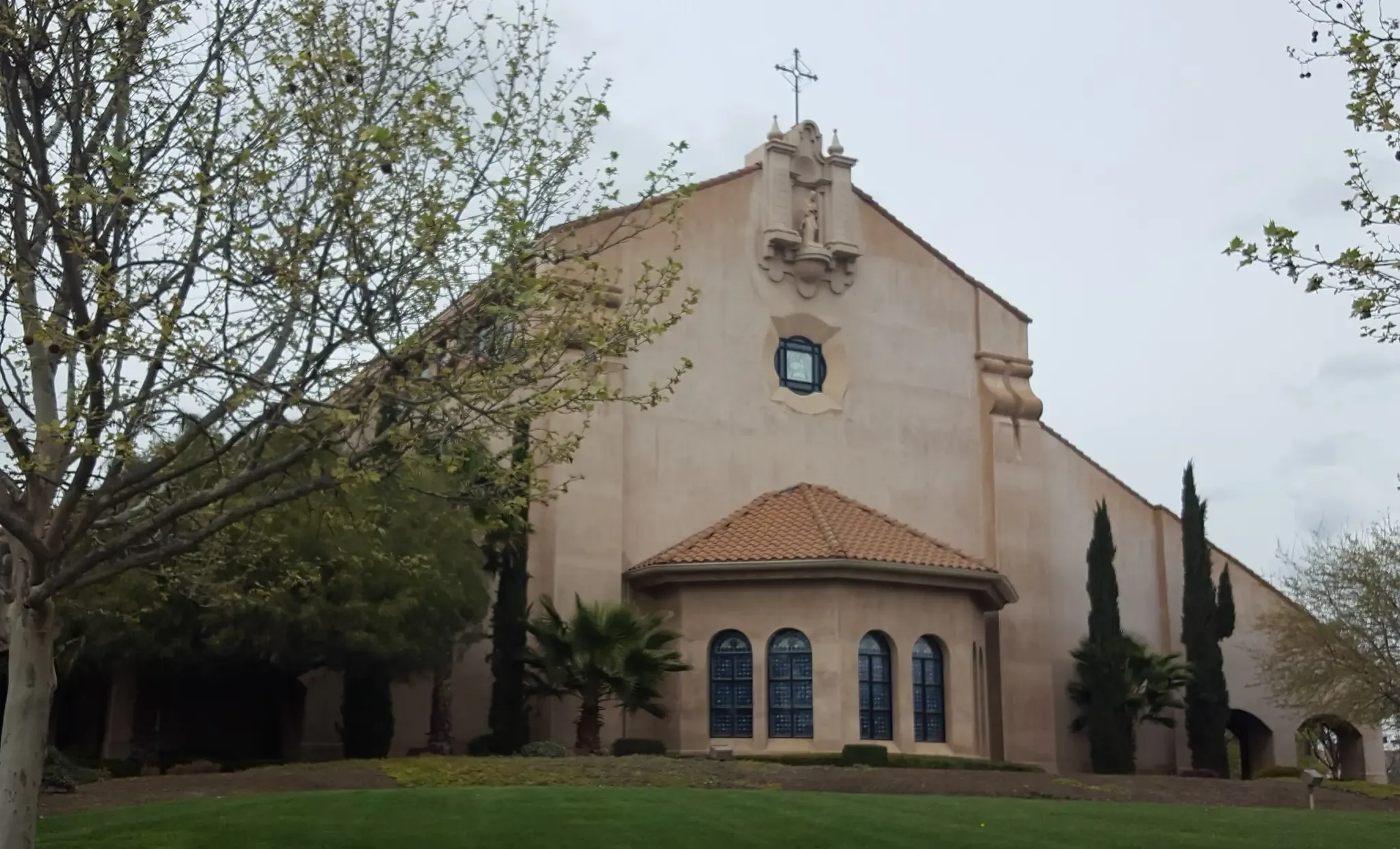 Large mission-style building with cross, green lawn, and trees under an overcast sky. - Mahany Nature Reserve loop
