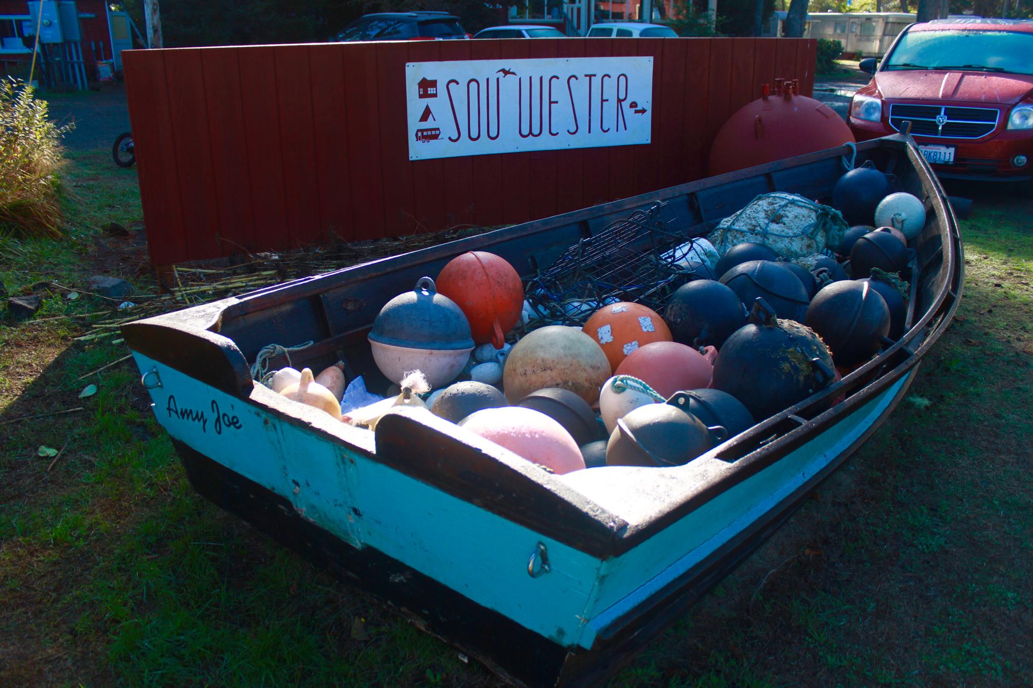Wooden boat filled with colorful fishing buoys on a sunny day.