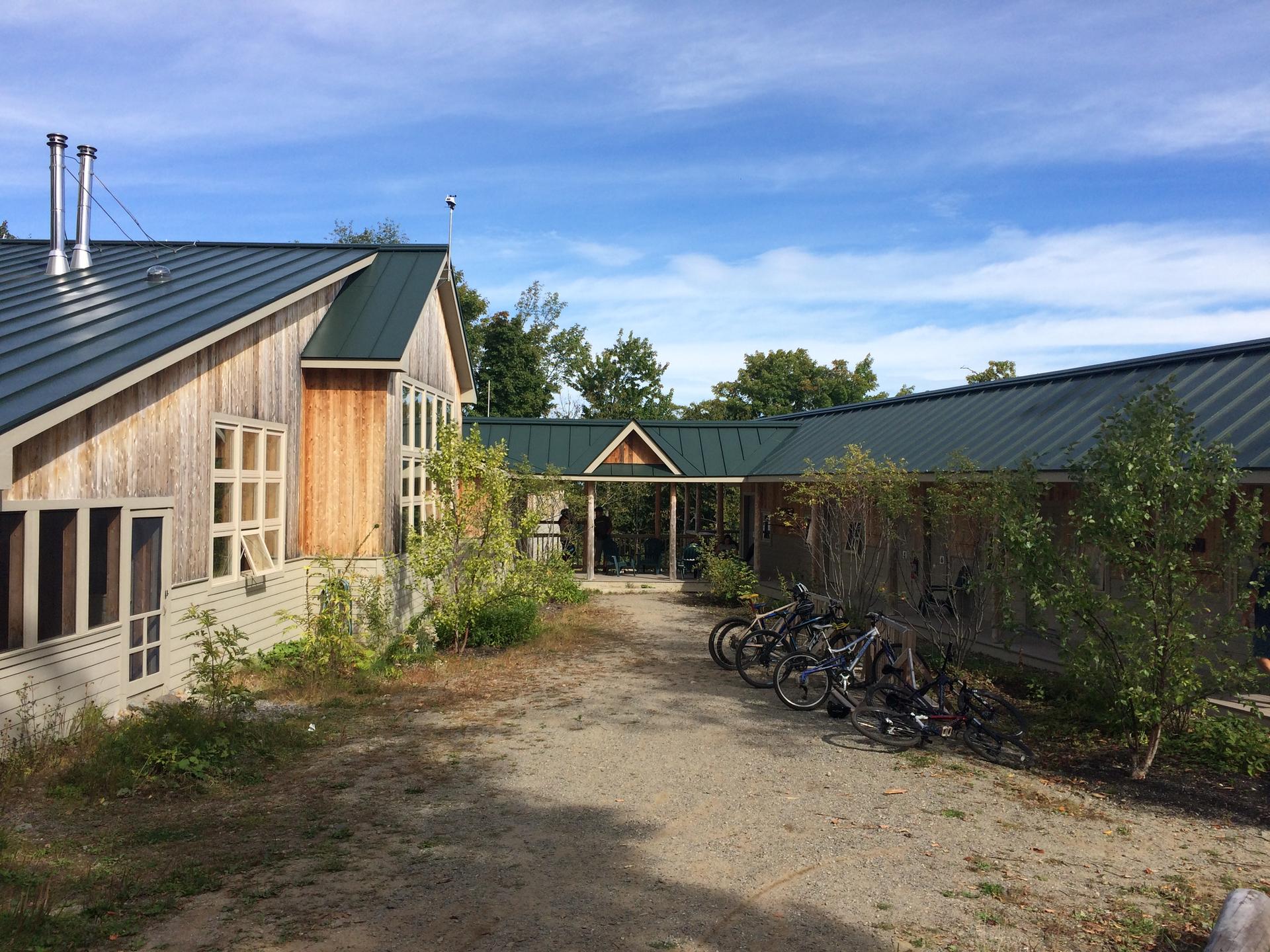 Rustic wooden building with a green roof and bicycles parked outside.