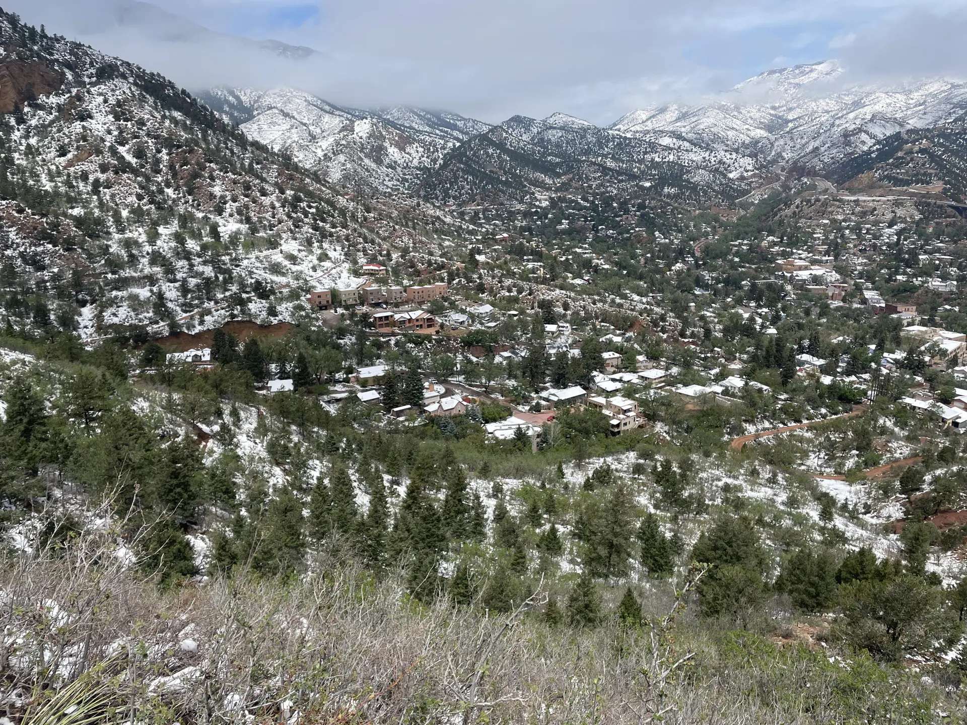 A snow-dusted town in a valley surrounded by forested, snow-capped mountains.