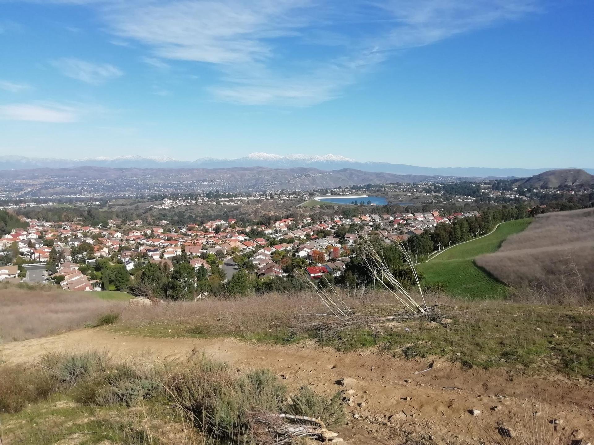 Panoramic view of a town and green fields under a bright blue sky.
