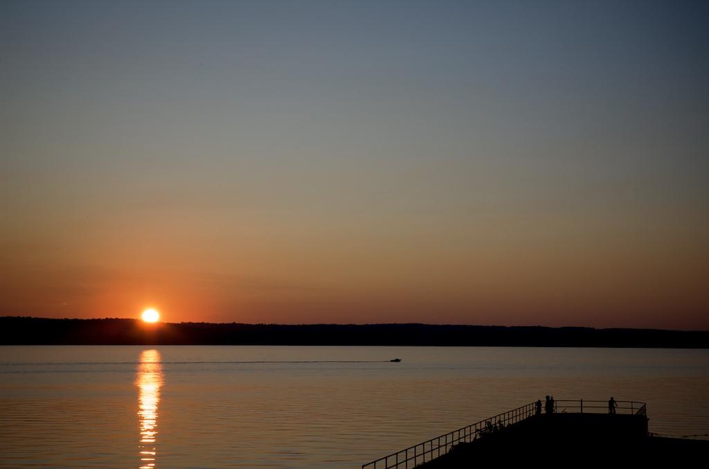 Golden sunset over a wide body of water with a silhouetted pier and people.