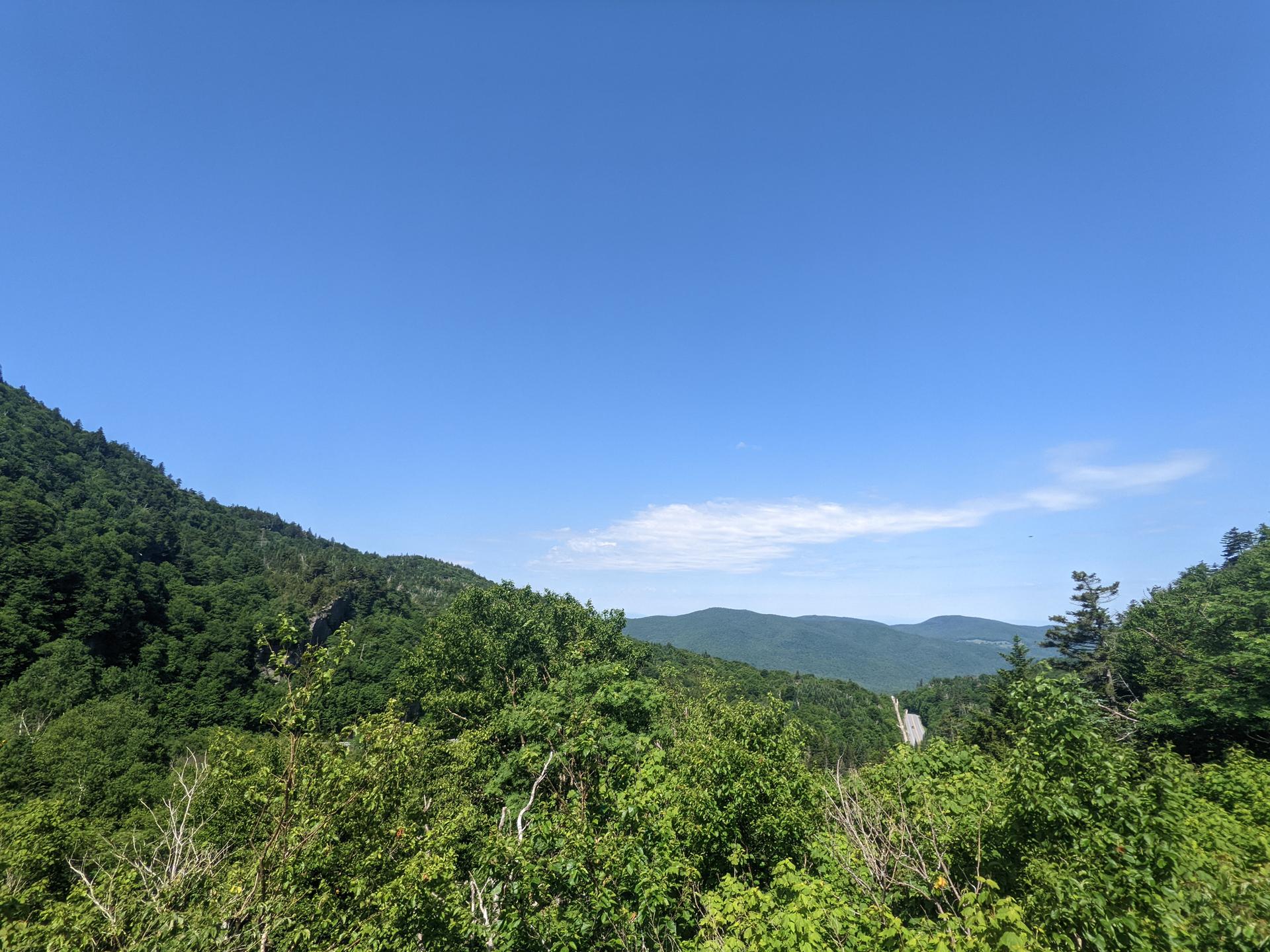 Lush green mountains under a clear blue sky on a bright day.