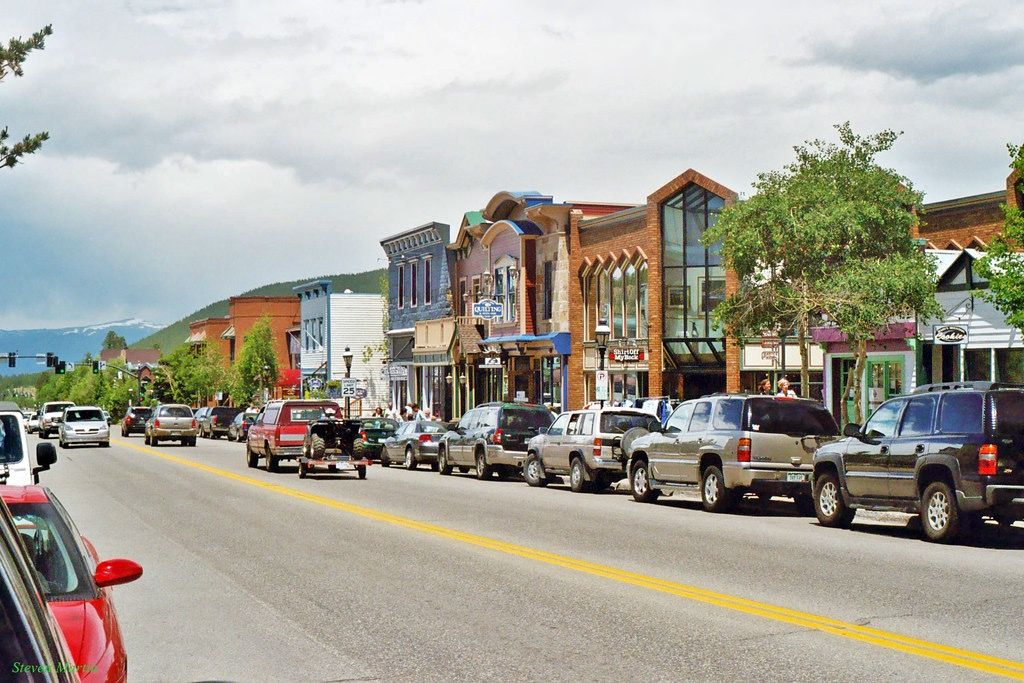 A bustling street lined with colorful buildings and parked cars under a cloudy sky. - Breckenridge – Old Town Breckenridge loop from Breckenridge