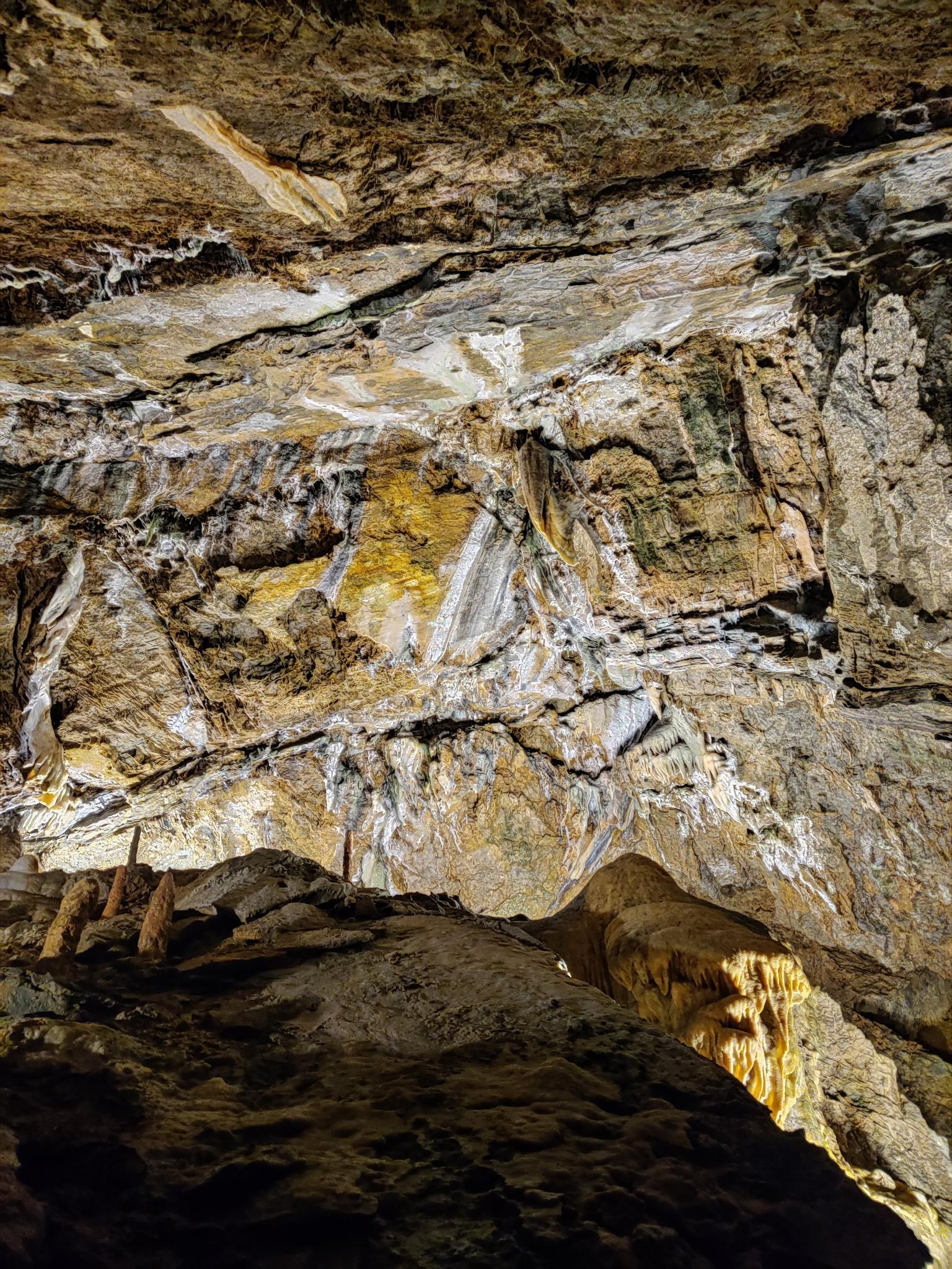 Illuminated cave interior with intricate rock formations and stalactites.