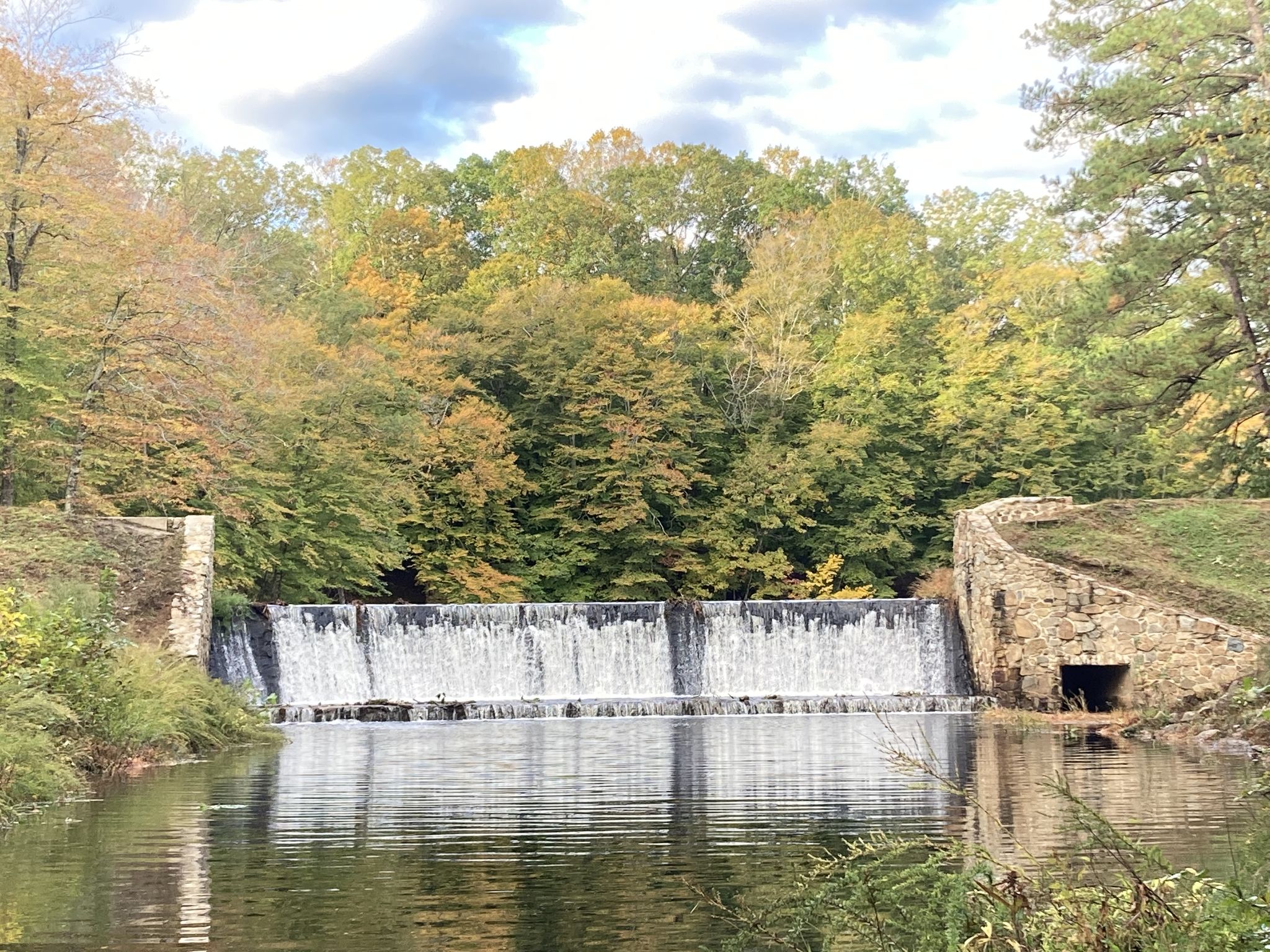 Wide waterfall over a river, surrounded by vibrant autumn trees. - Old Mill Bicycle Trail