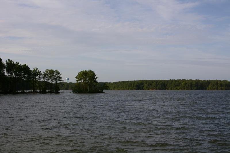 A wide lake with a small island and distant forested shoreline.