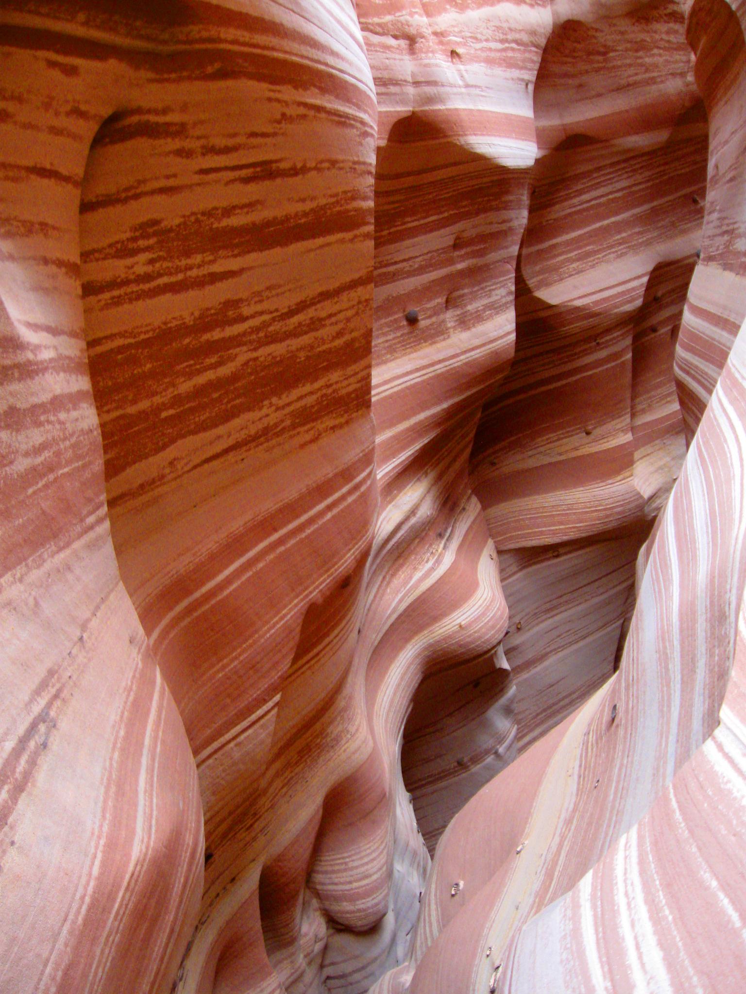 Close-up of a slot canyon wall with vibrant red and white striped rock.
