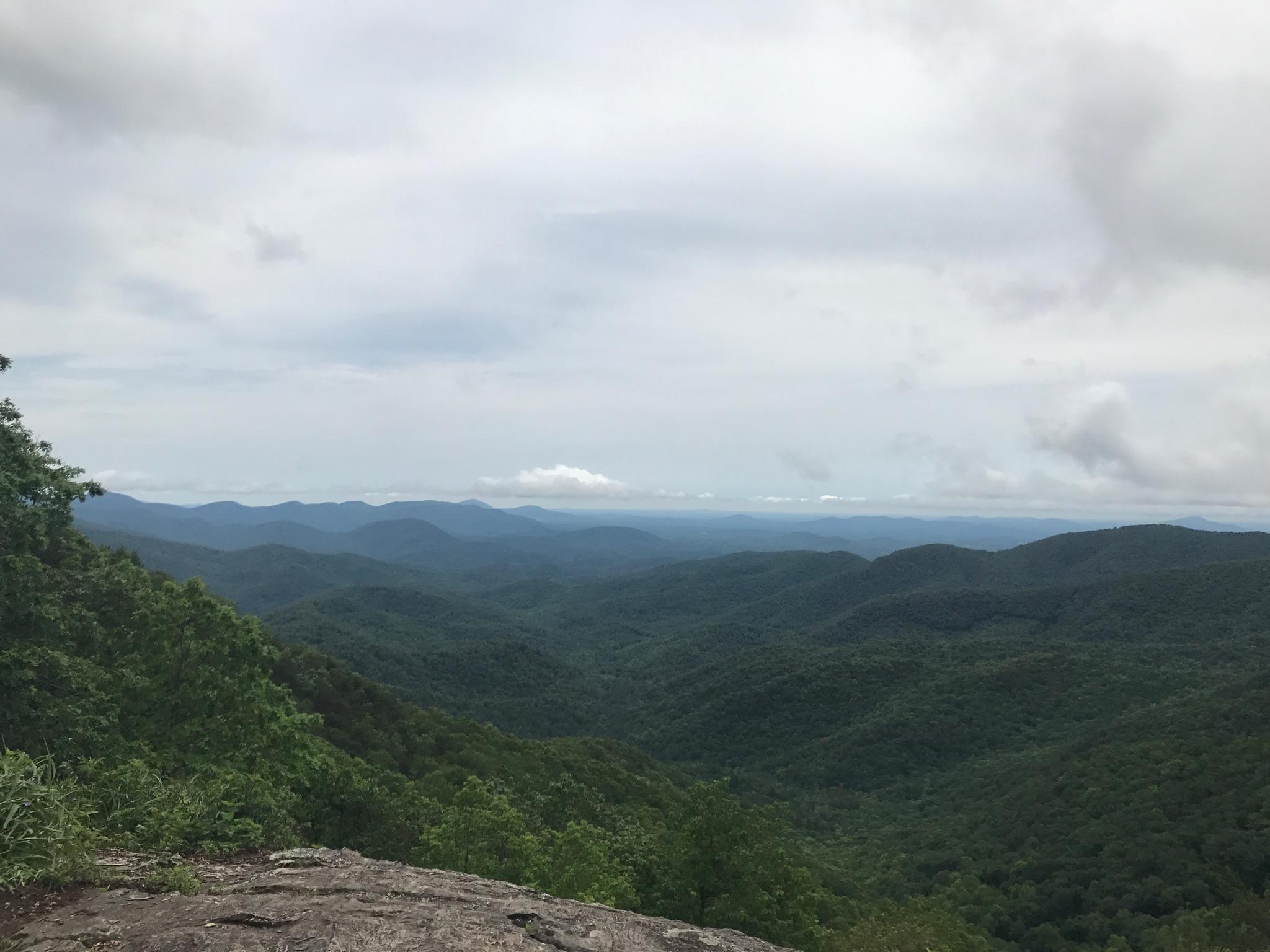 Wide view of rolling green mountains under a cloudy sky.