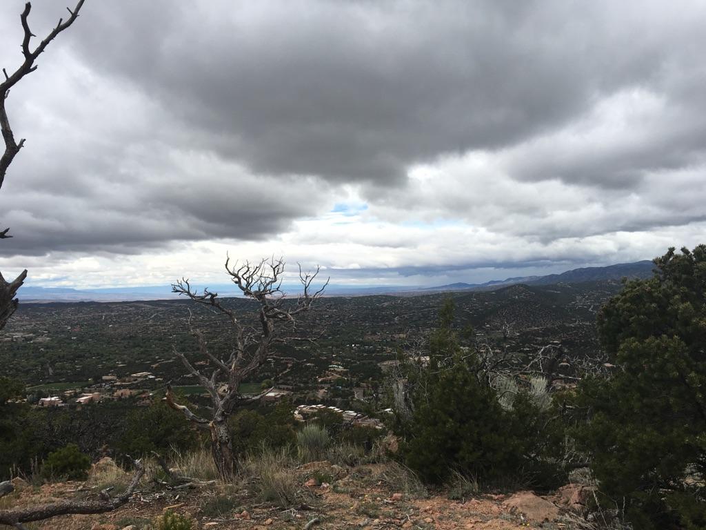 Overcast sky above a vast valley with scattered buildings and dry trees.