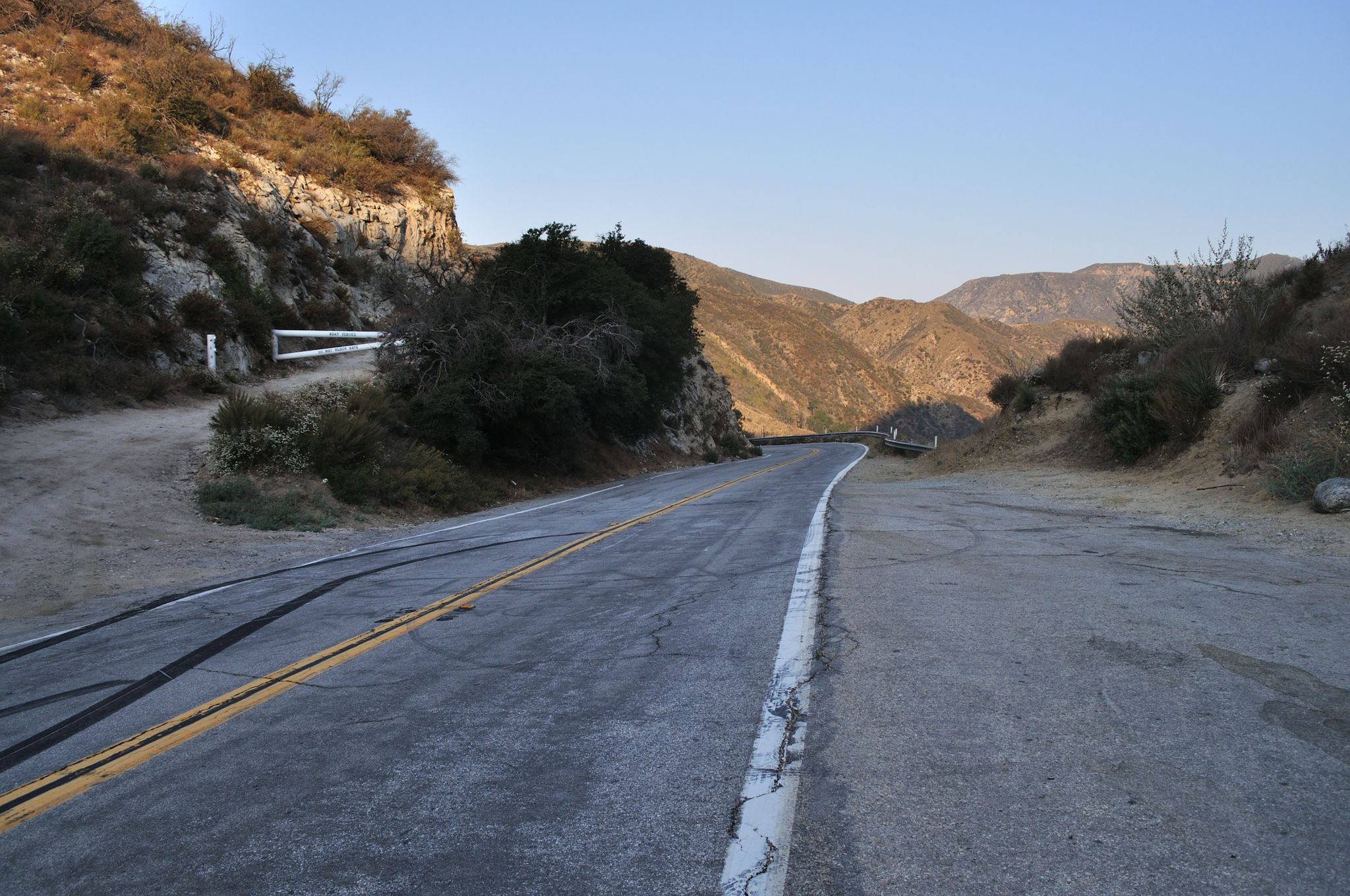 Winding mountain road at dusk, with hills and distant mountains. - Bear Divide – Dillon Divide loop from Vista Canyon