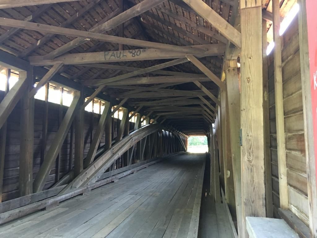 Inside a long, old wooden covered bridge with visible beams and dim light. - Maiden Creek loop