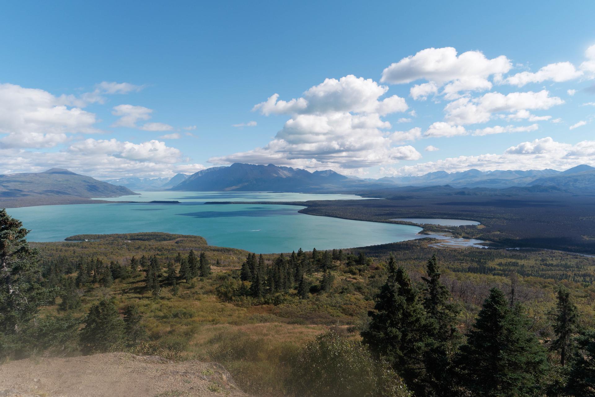 Panoramic view of a large blue lake surrounded by mountains and forests.
