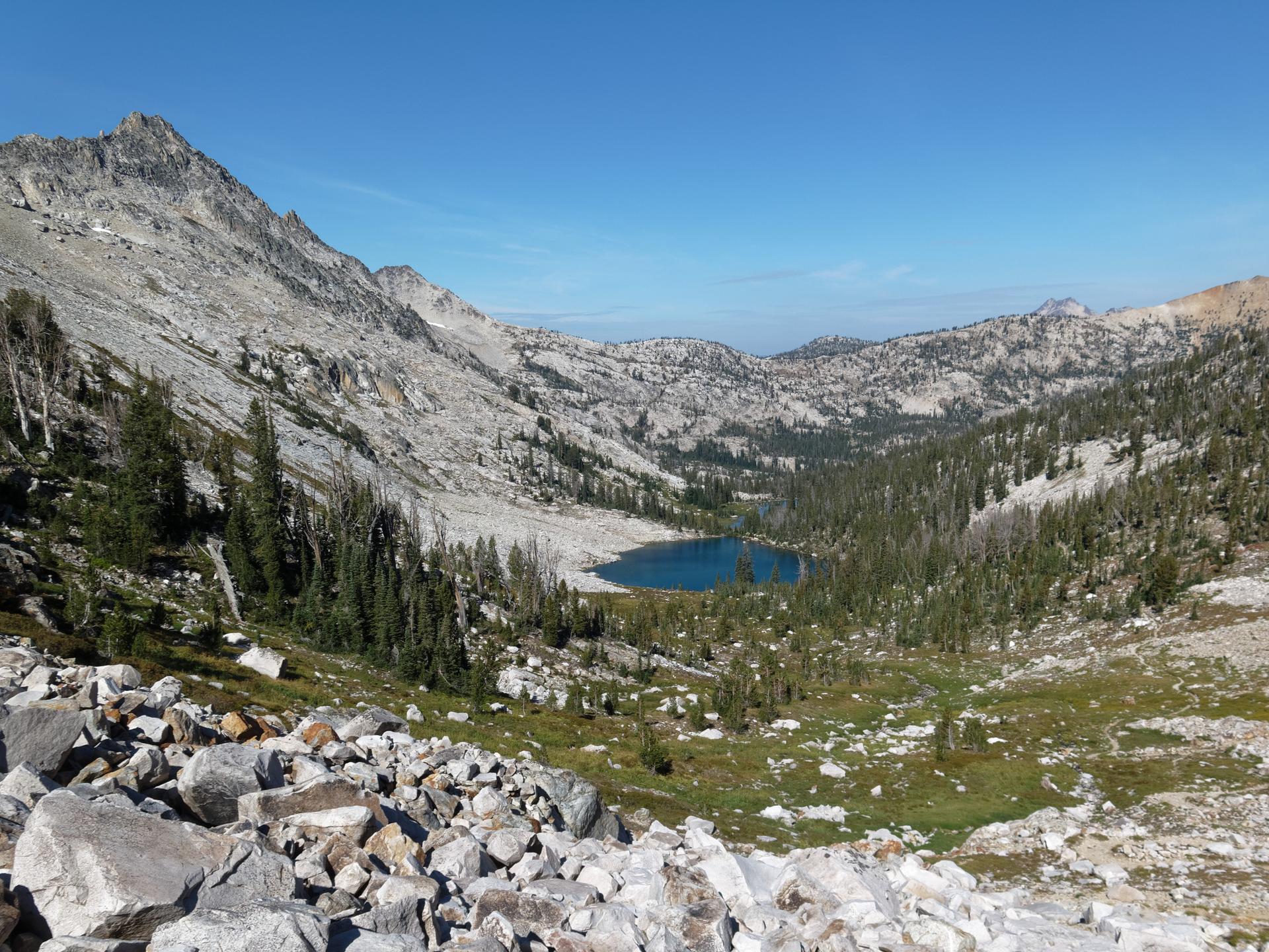 Panoramic view of a rocky mountain valley with a small blue lake.