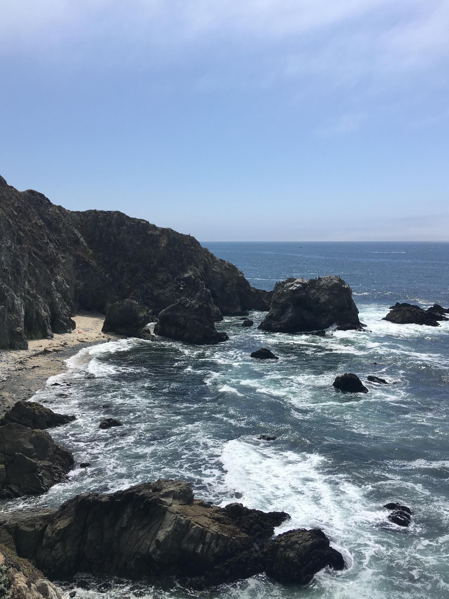 Coastal cliffs, rocky beach, and ocean waves under a bright sky. - Tomales Point Trail
