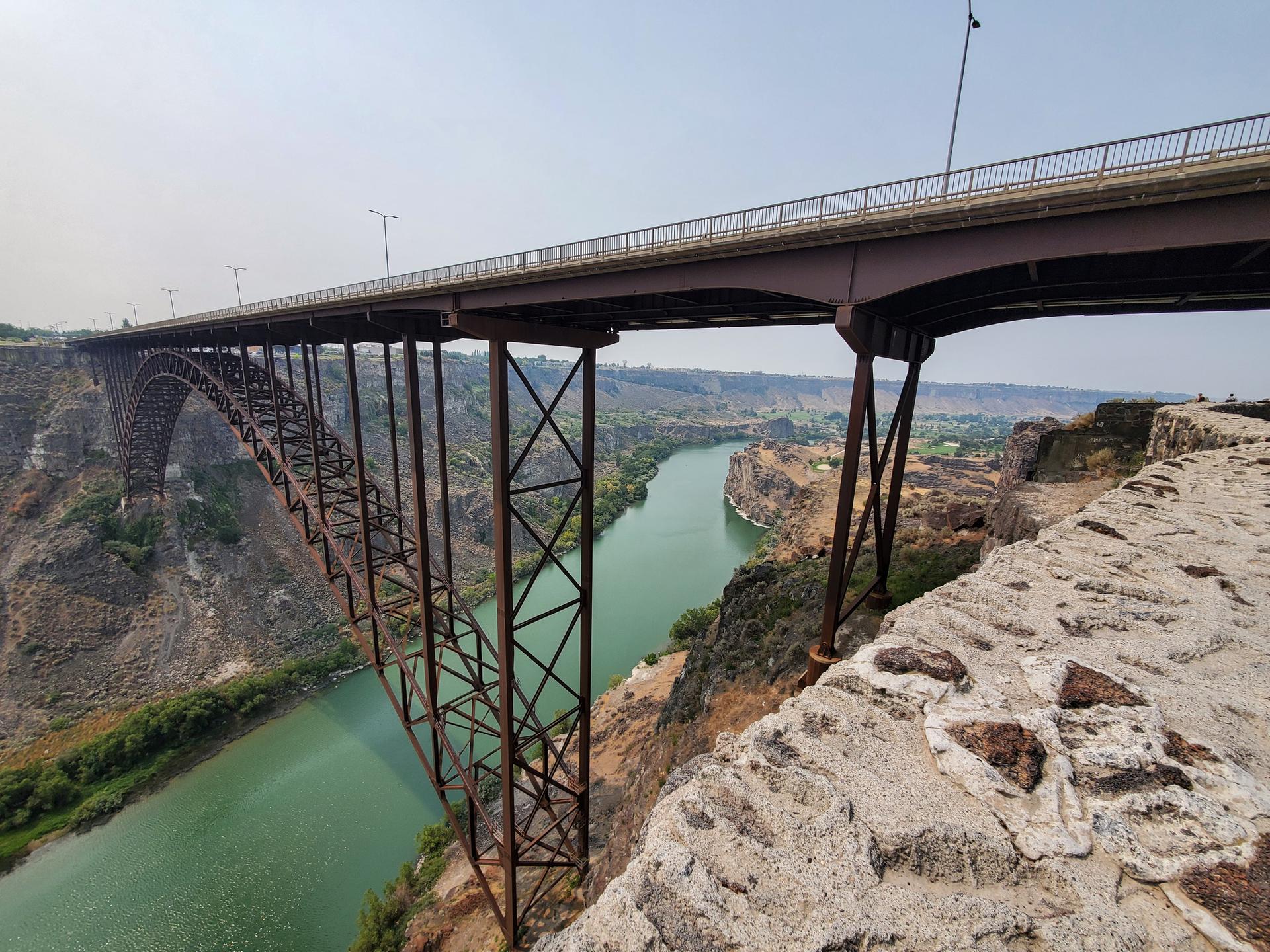 Large steel arch bridge spans a wide river in a deep canyon.