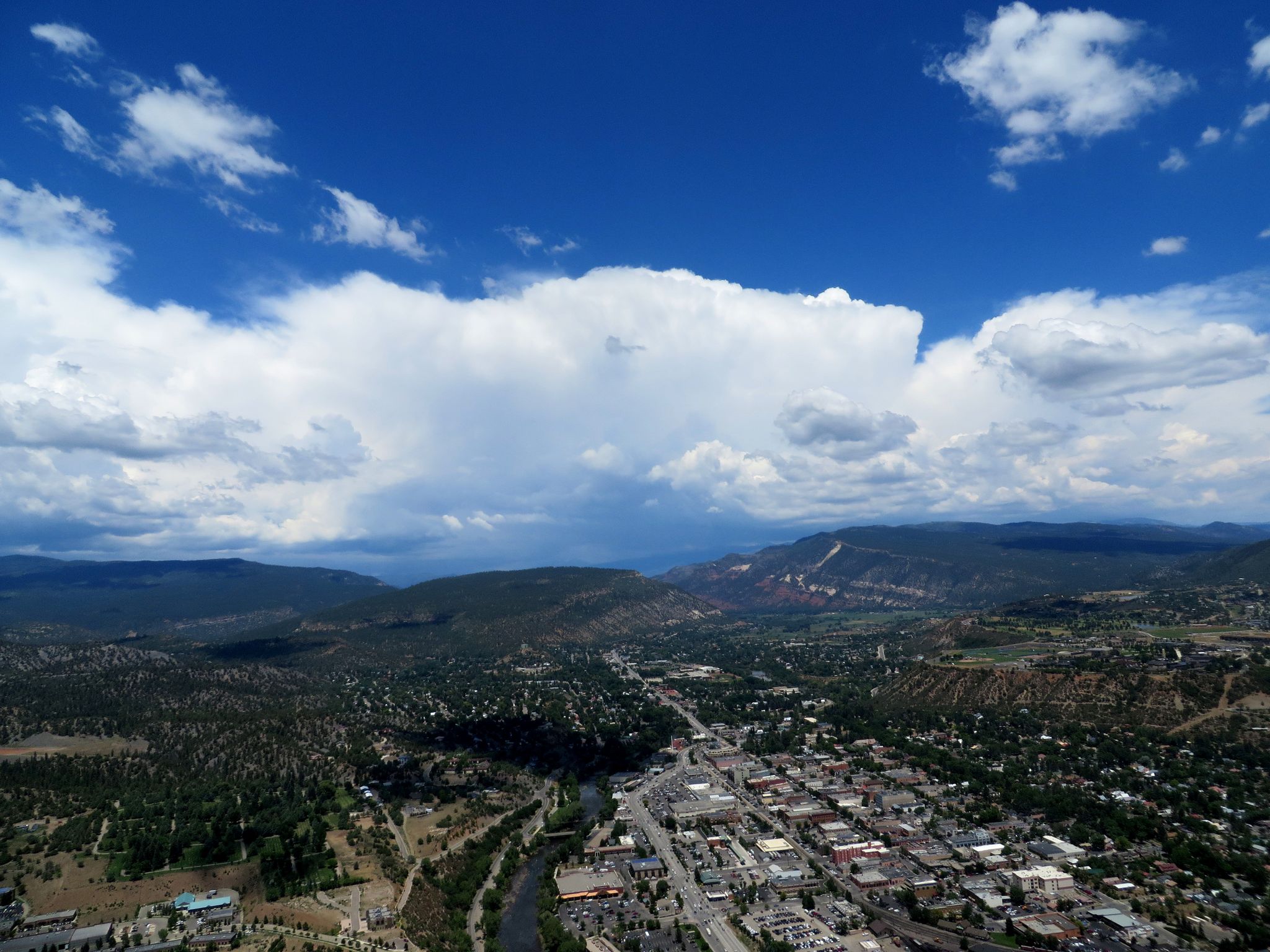 Aerial view of a town, river, and mountains under a dramatic cloudy sky. - Smelter Mountain