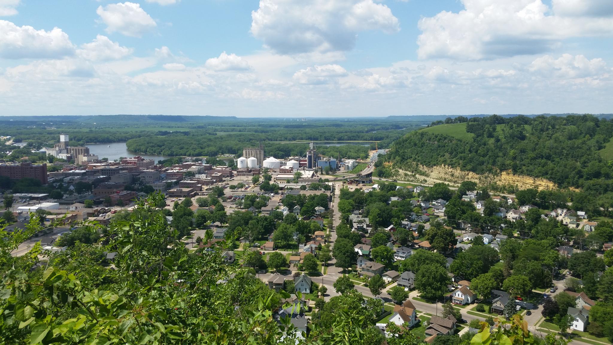 Panoramic view of a town and river from a high, green vantage point.