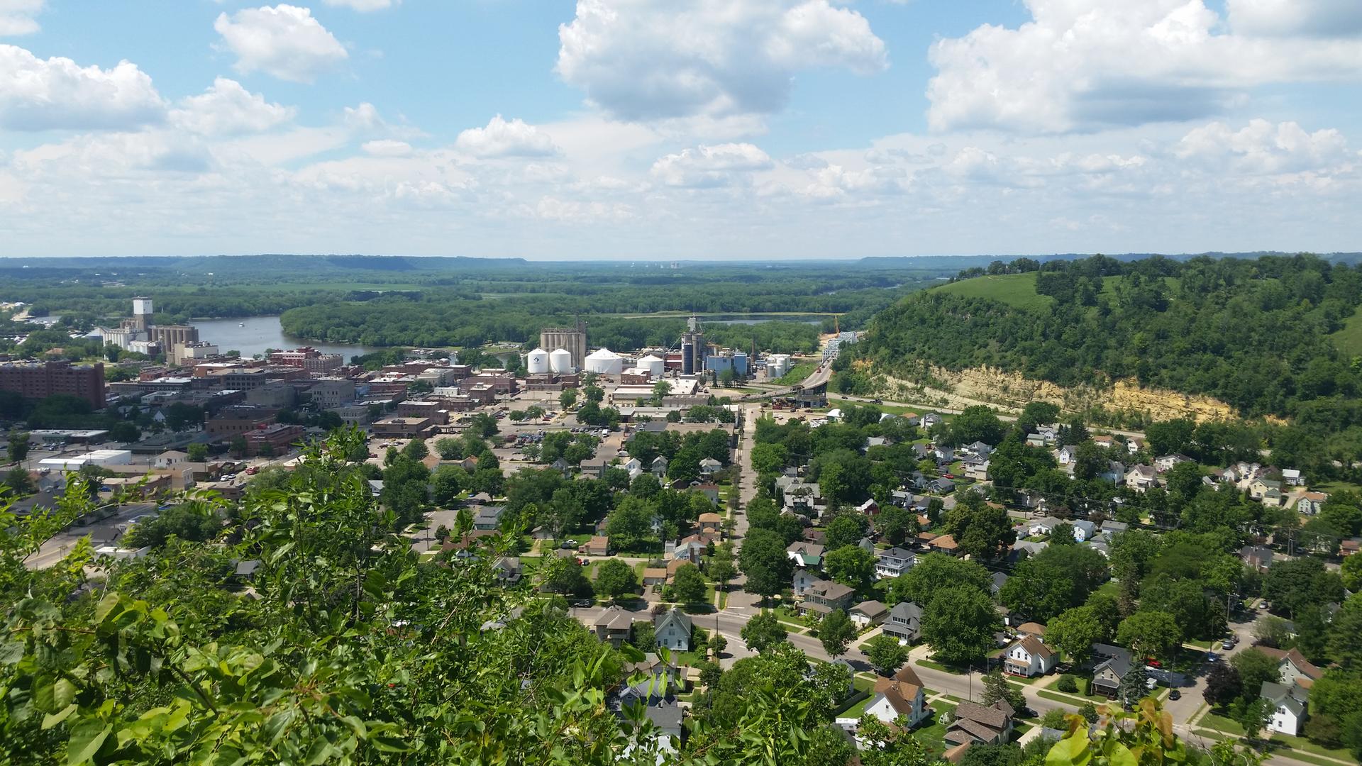 Panoramic view of a town and river from a high, green vantage point.