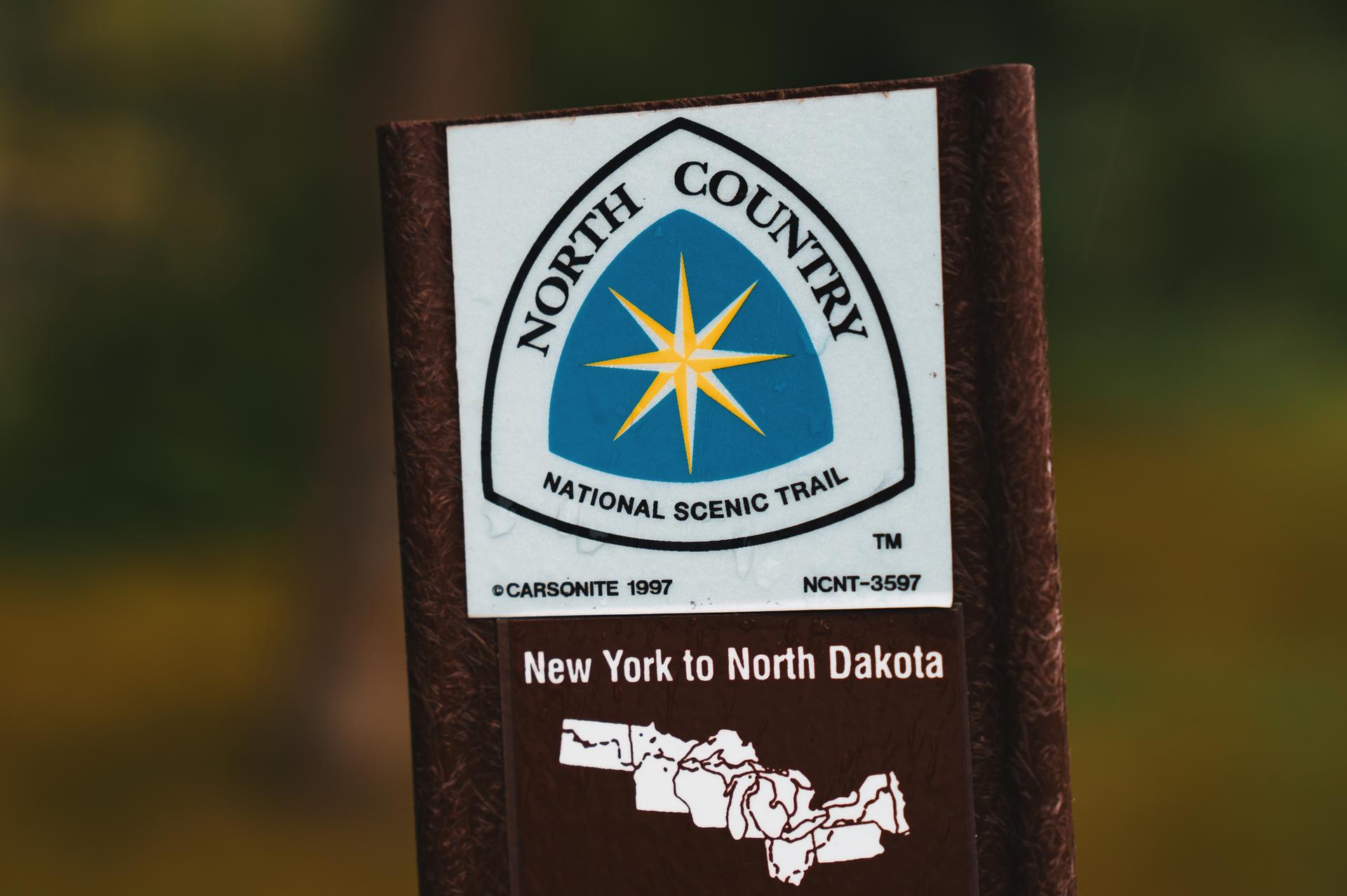 Close-up of a trail sign with a blue and yellow star logo.