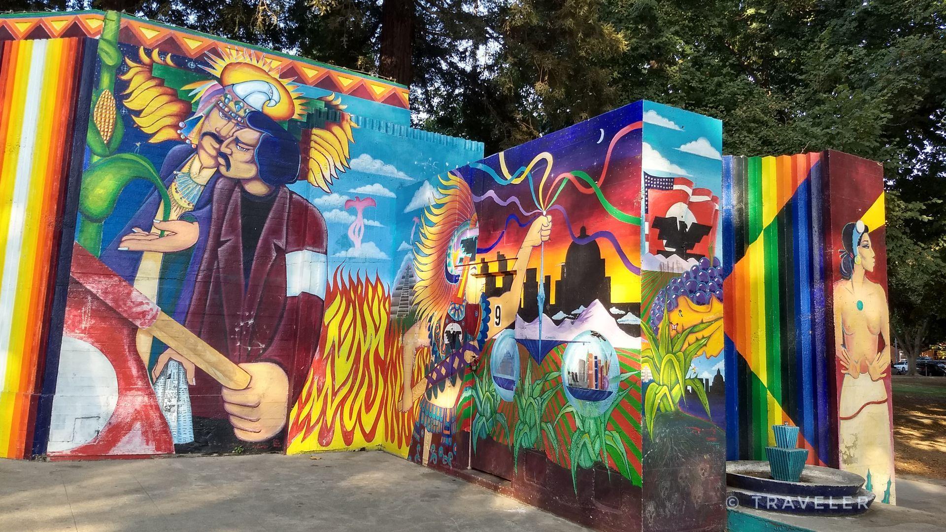 Vibrant, colorful mural with human figures and abstract designs on outdoor walls.