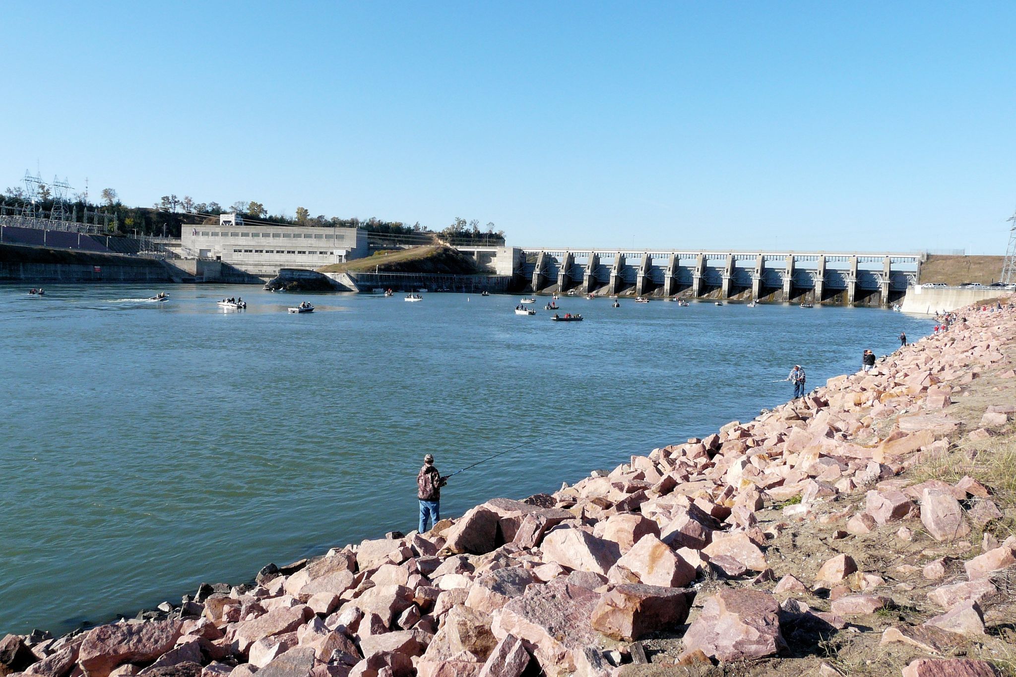 Sunny day, people fishing from boats and rocky shore near a large dam. - Lake Yankton loop