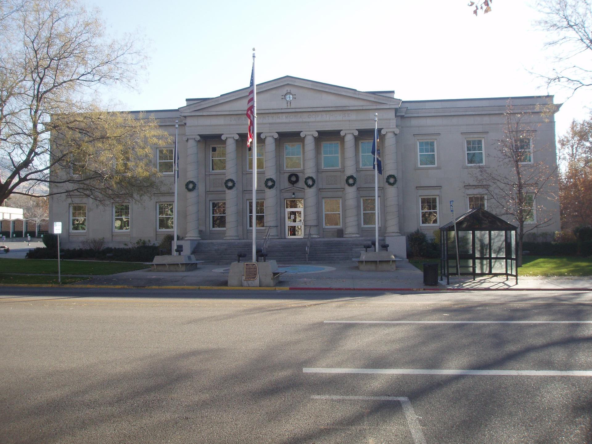A large, classical building with columns and flags under bright daylight.