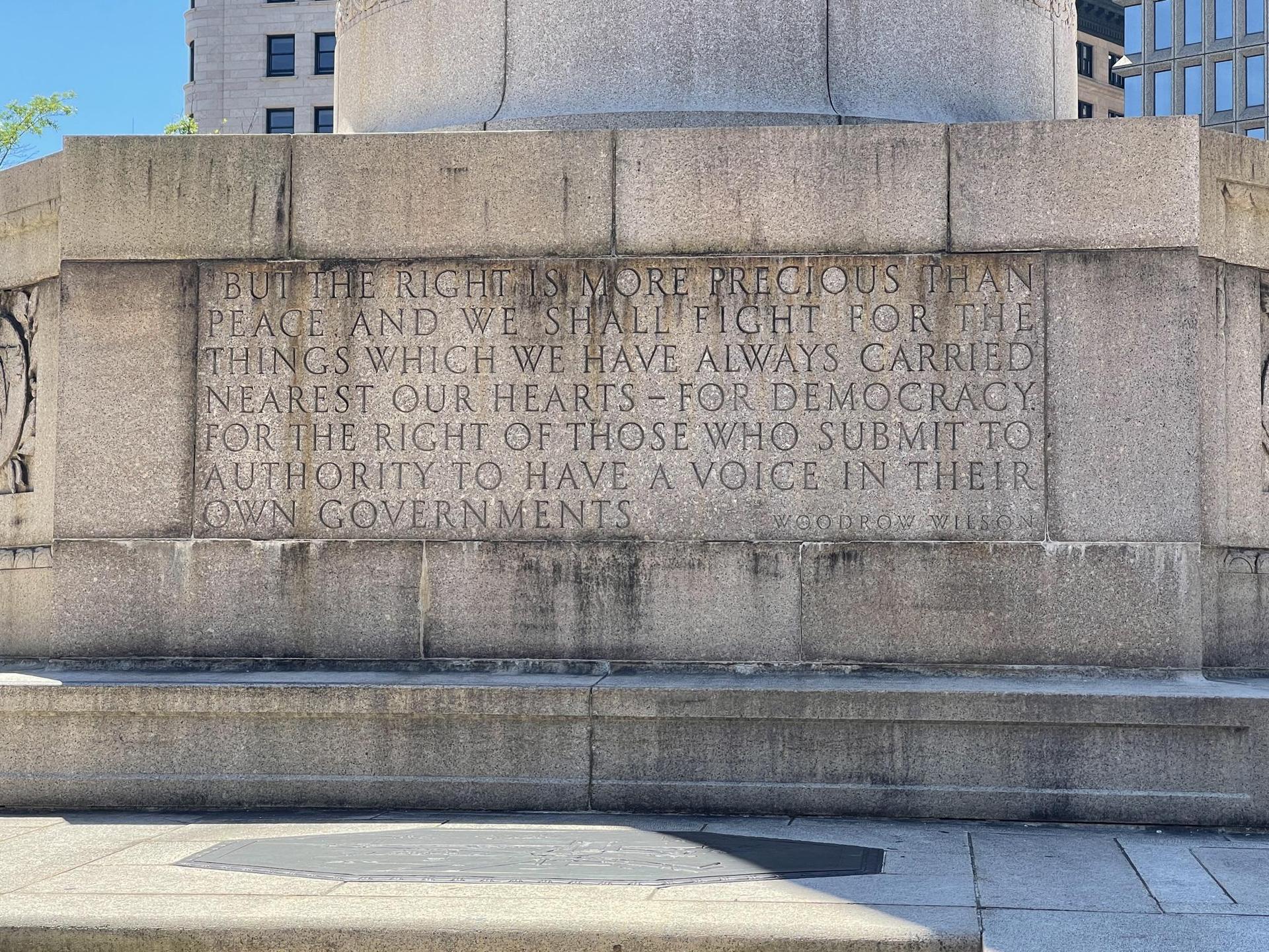 Close-up of a stone monument with engraved text under bright sunlight.