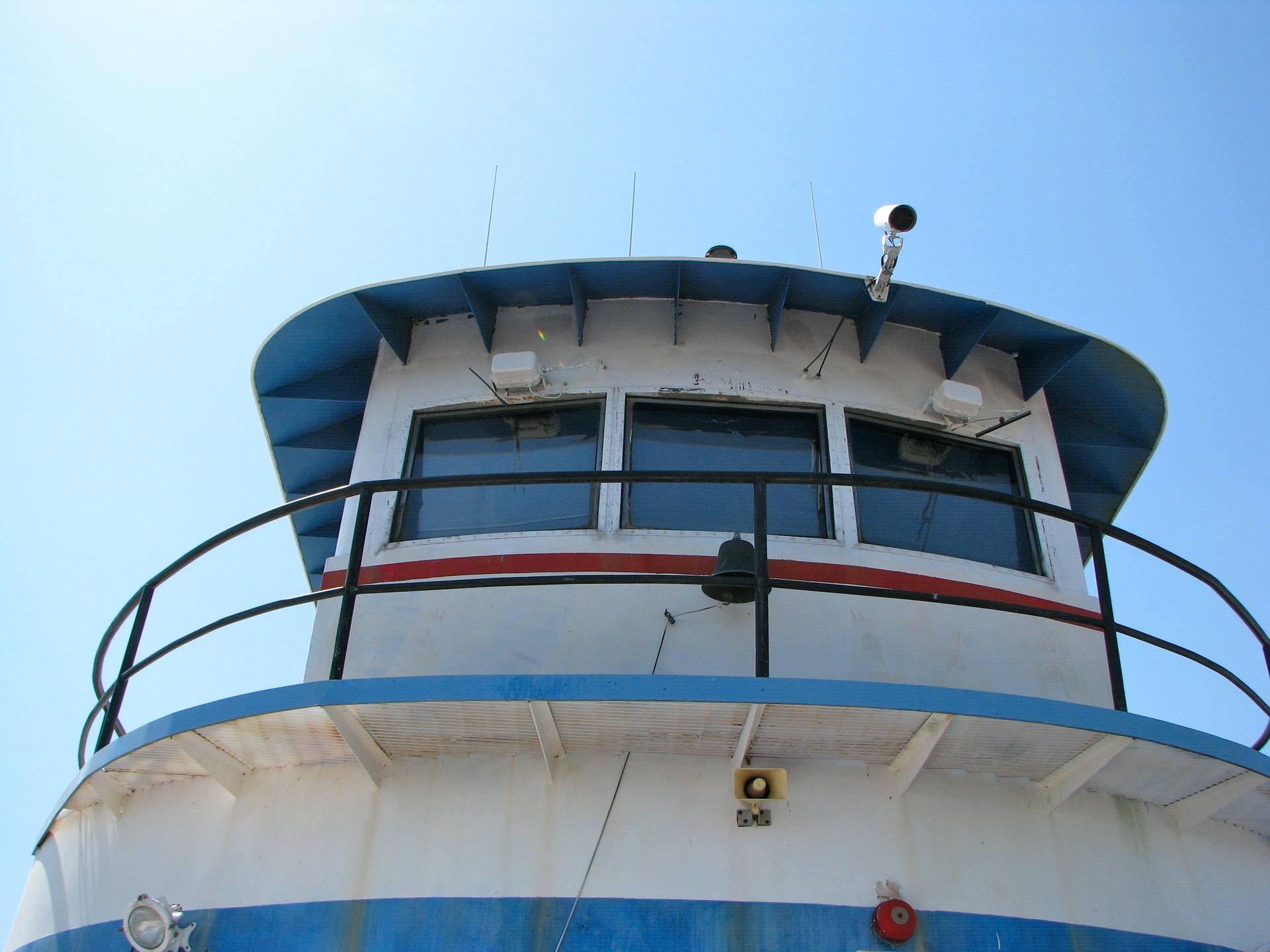 Close-up of a boat's white and blue cabin against a clear blue sky.