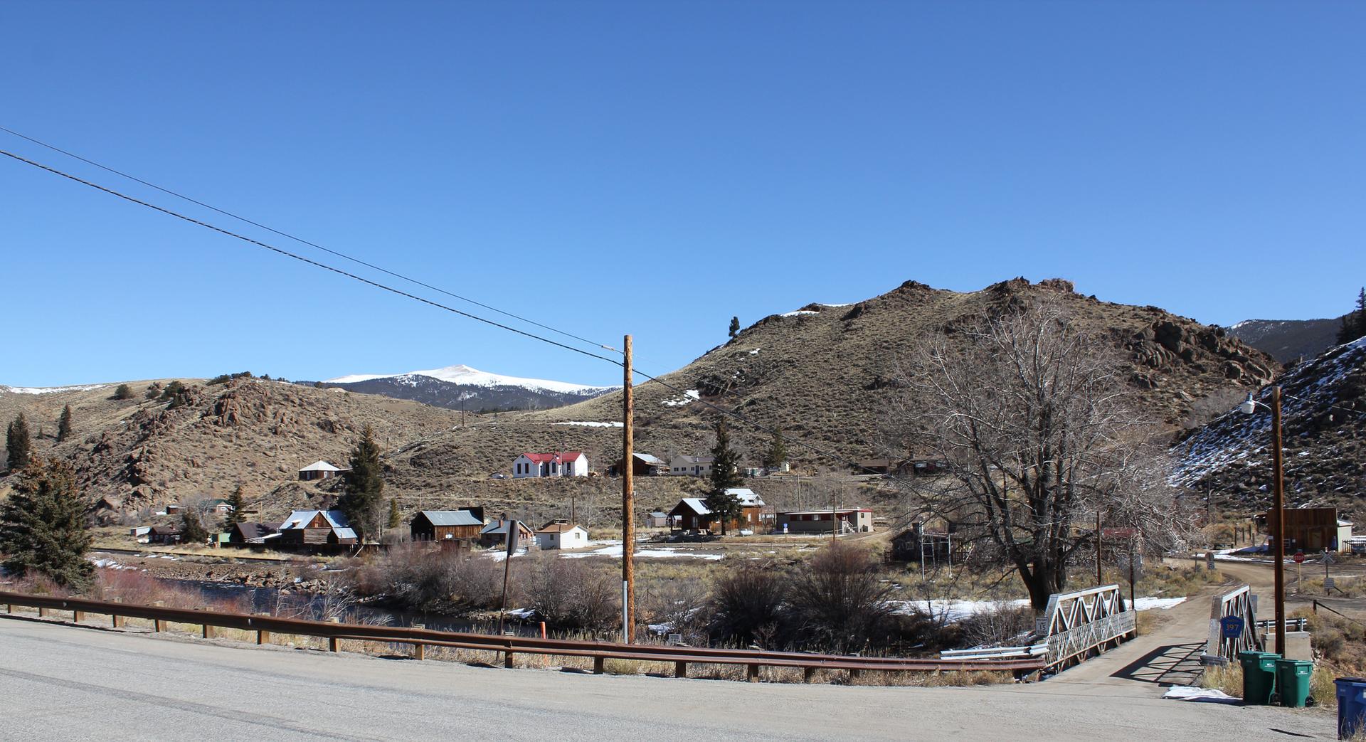 A small village with houses by a river, surrounded by dry hills.