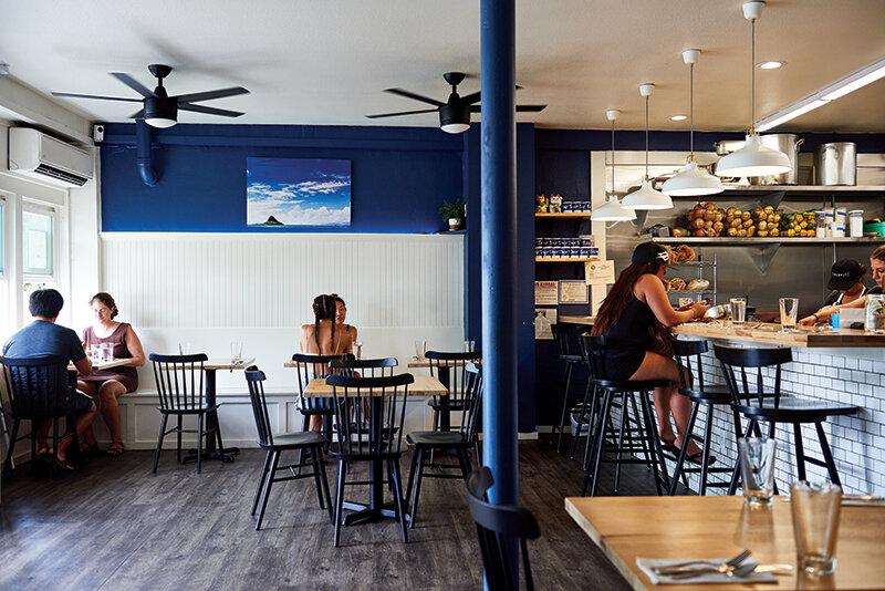 People dining in a brightly lit restaurant with blue walls and wooden floors.