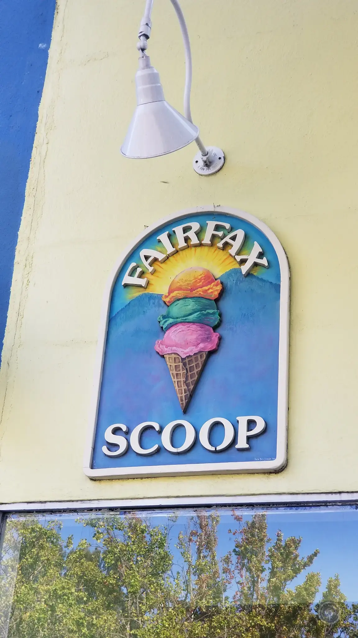 Close-up of a colorful ice cream shop sign on a yellow wall.