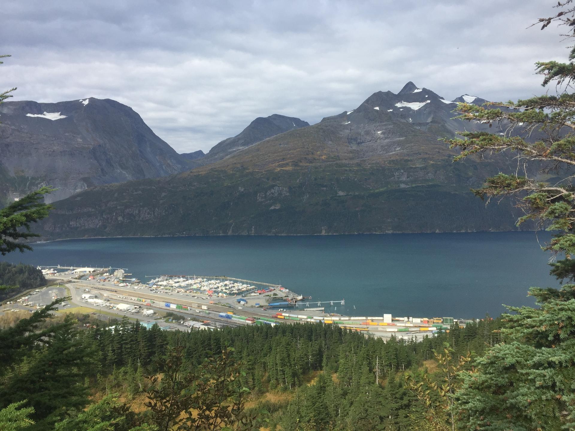 Overhead view of a bustling port town nestled in a bay surrounded by mountains.