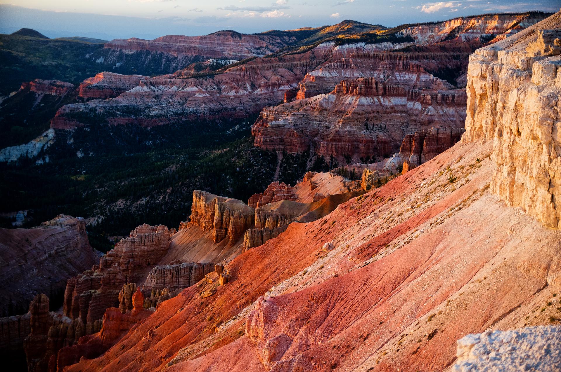 Dramatic canyon landscape with vibrant red and white rock formations in golden light.