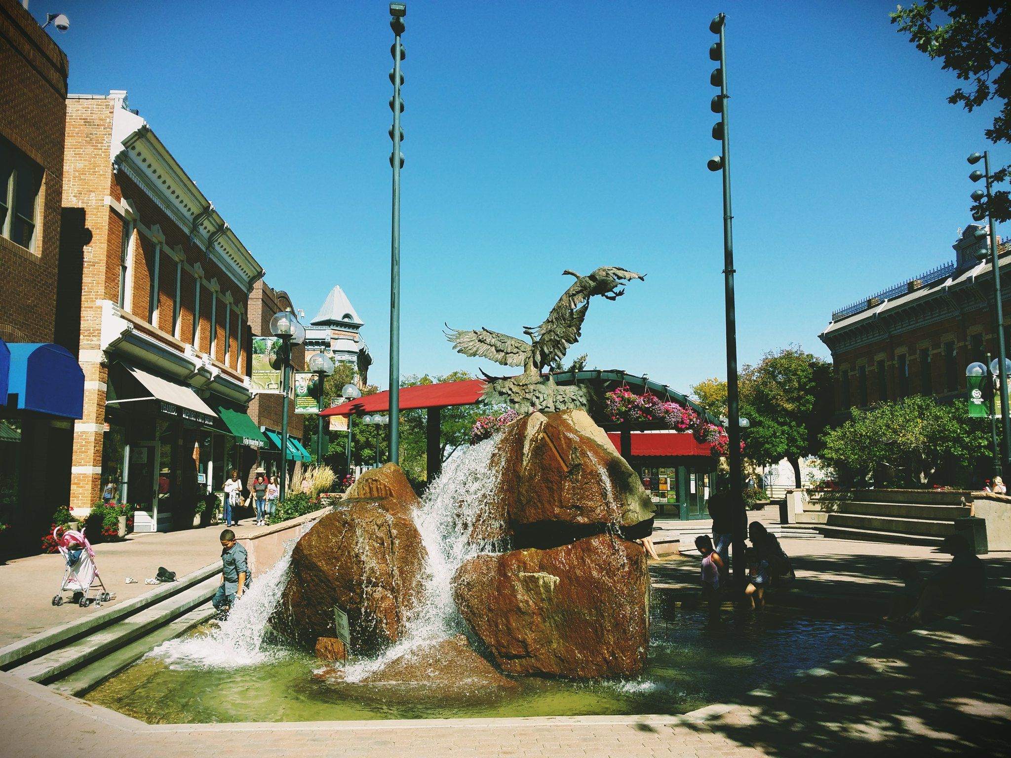 Large fountain with an eagle sculpture in a sunny town square with people. - Northeast loop and New Belgium Brewery