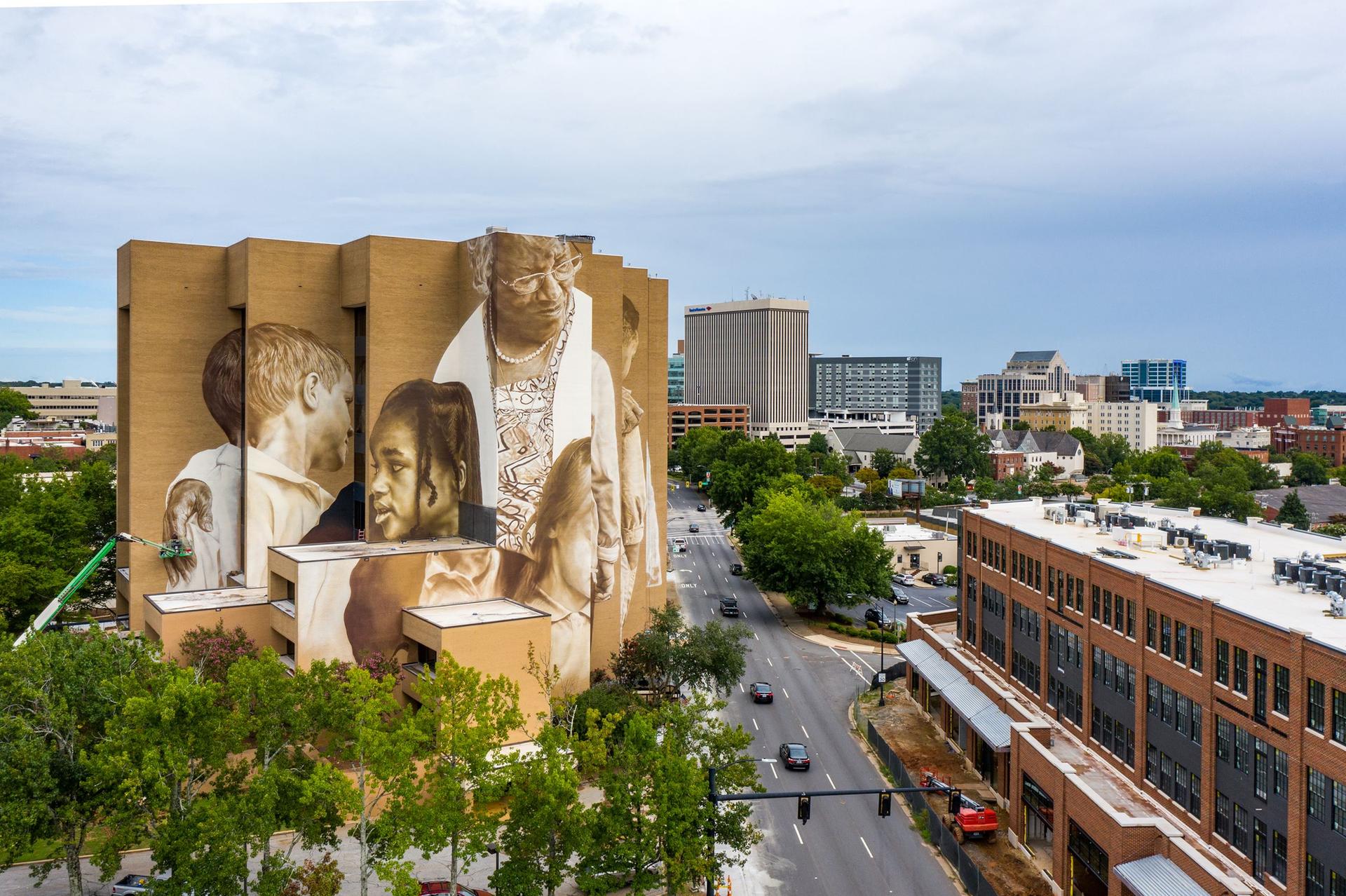 An aerial view of a city building with a large mural of diverse faces.