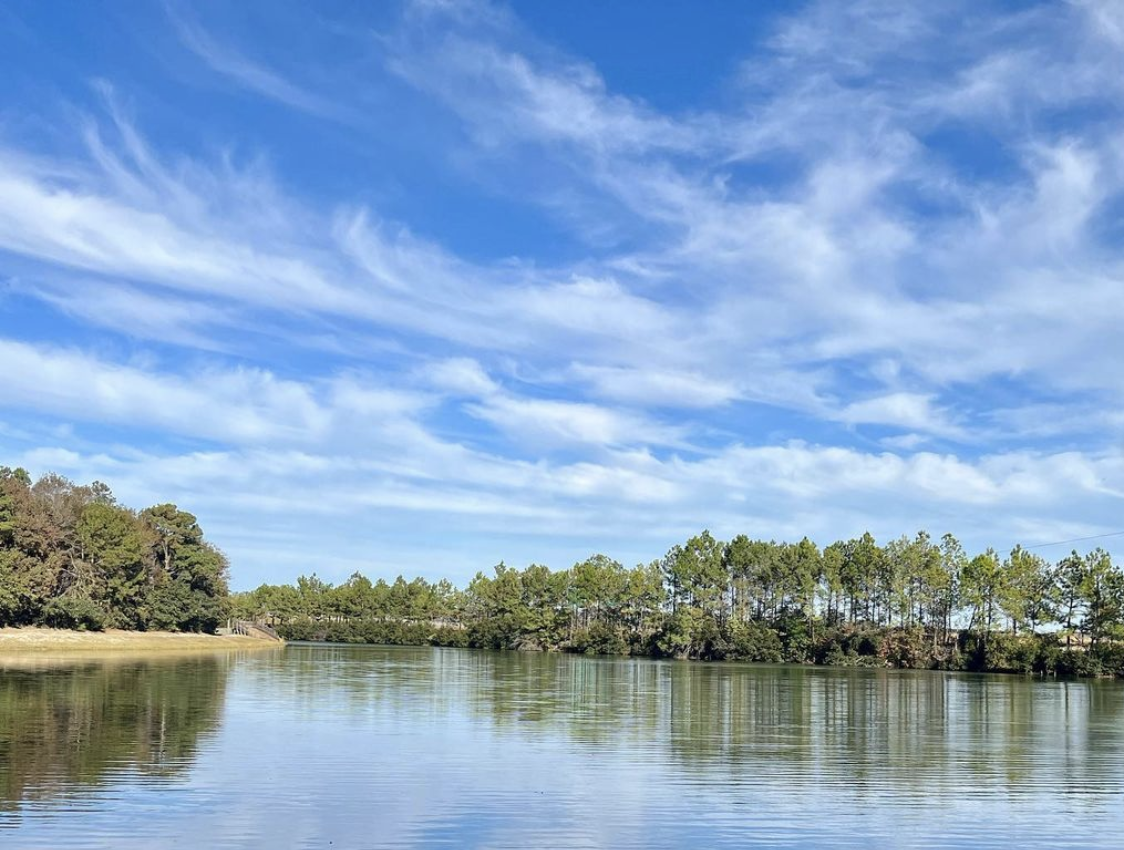 A calm lake reflecting a dramatic blue sky with wispy clouds.