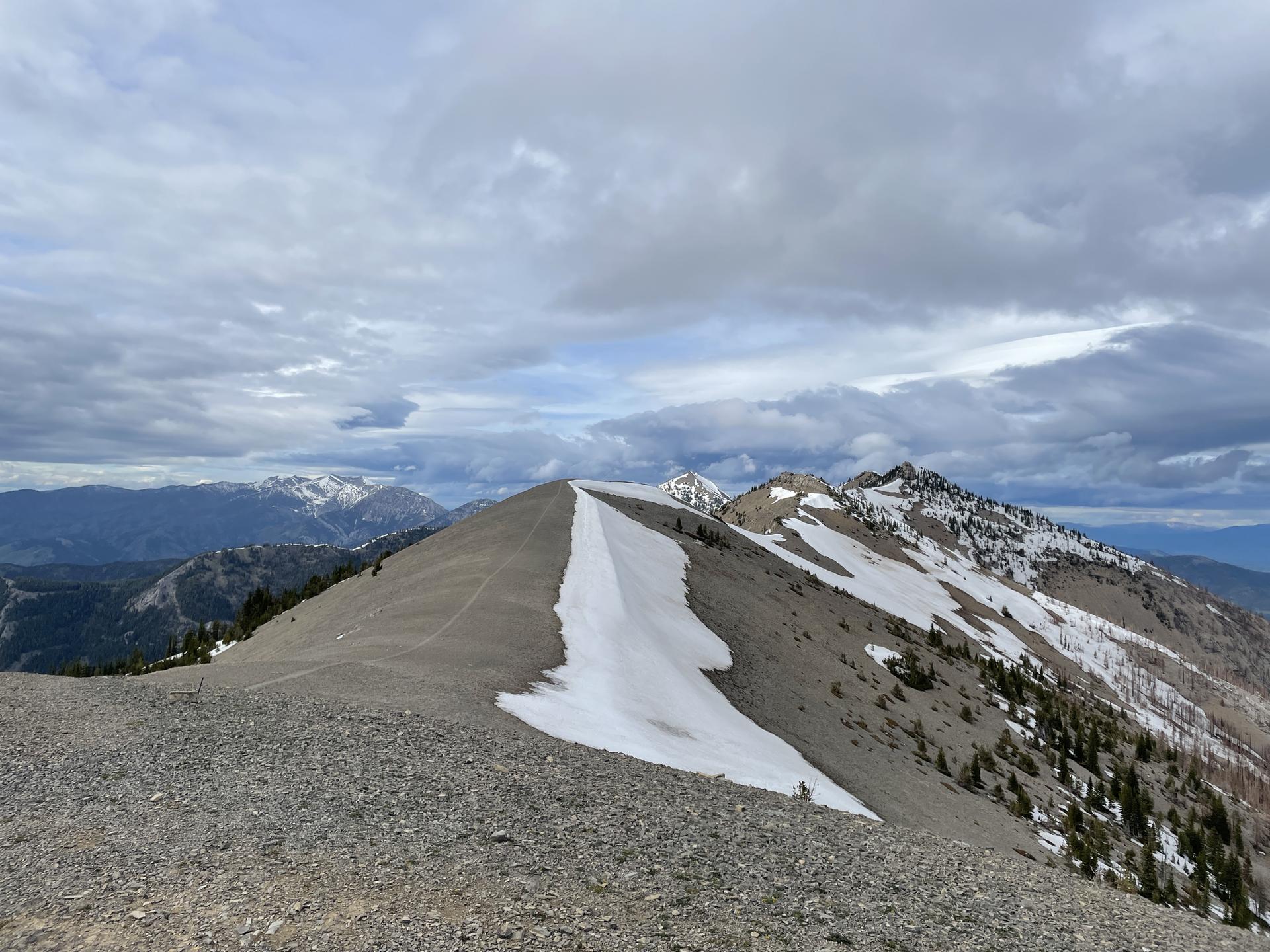 Snow patches on a rocky mountain ridge under a dramatic cloudy sky.