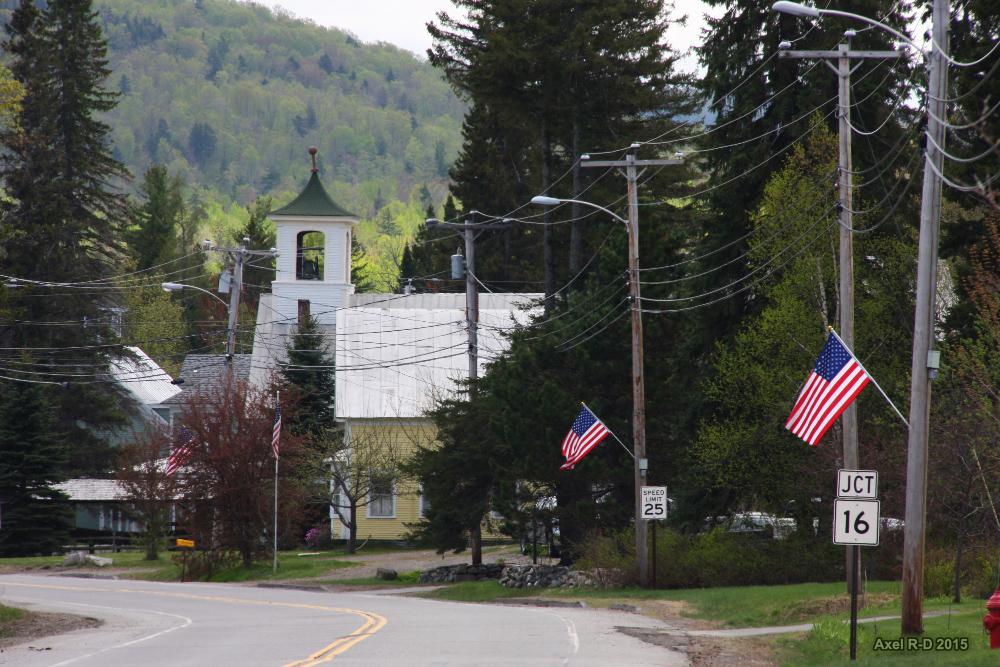 A white church, American flags, and a winding road on a bright day.