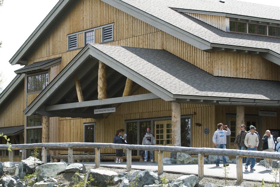 Large wooden building with a covered entrance and people on a walkway.