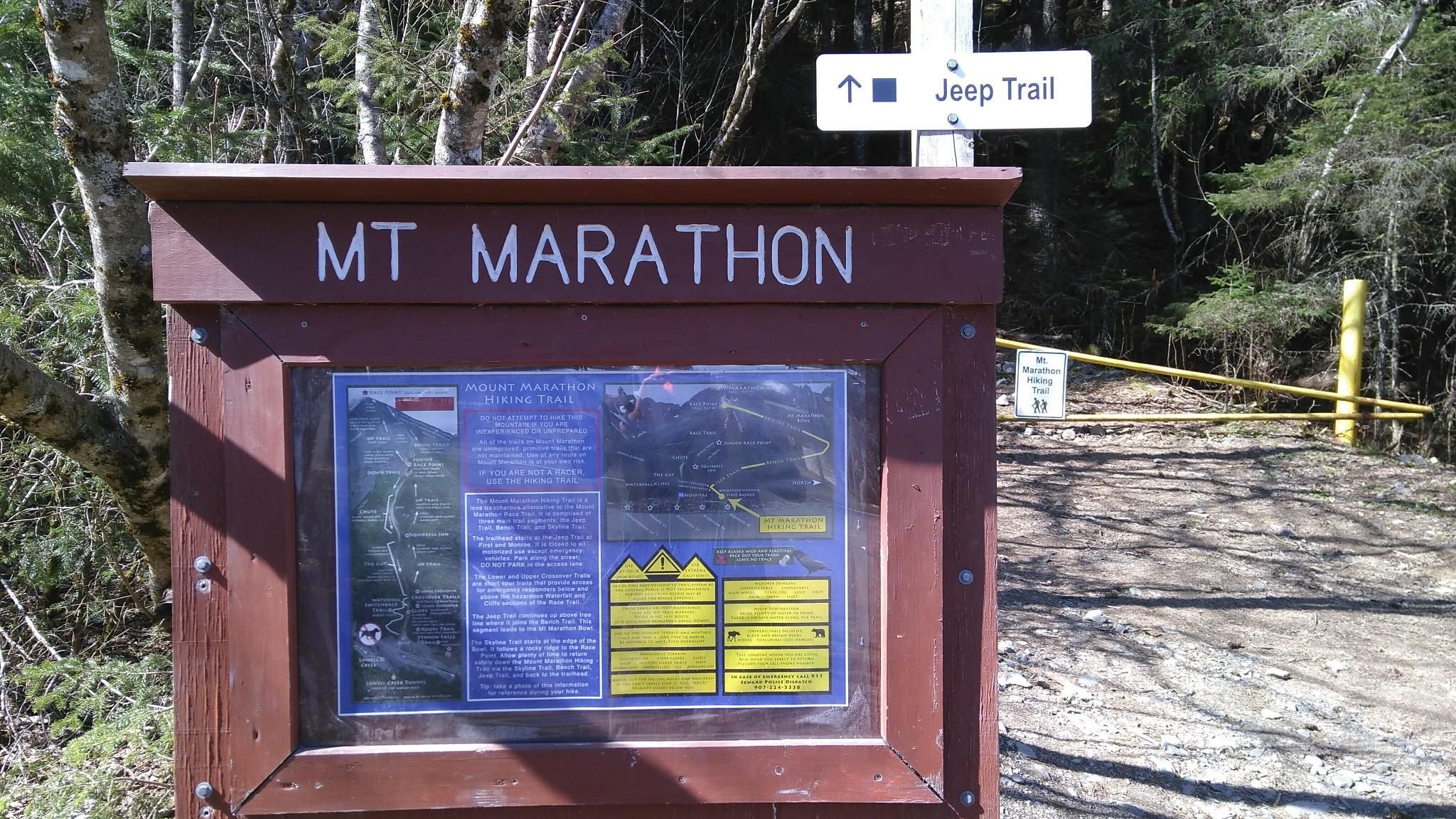 A wooden information board and a 'Jeep Trail' sign in a forest. - Mount Marathon Trail