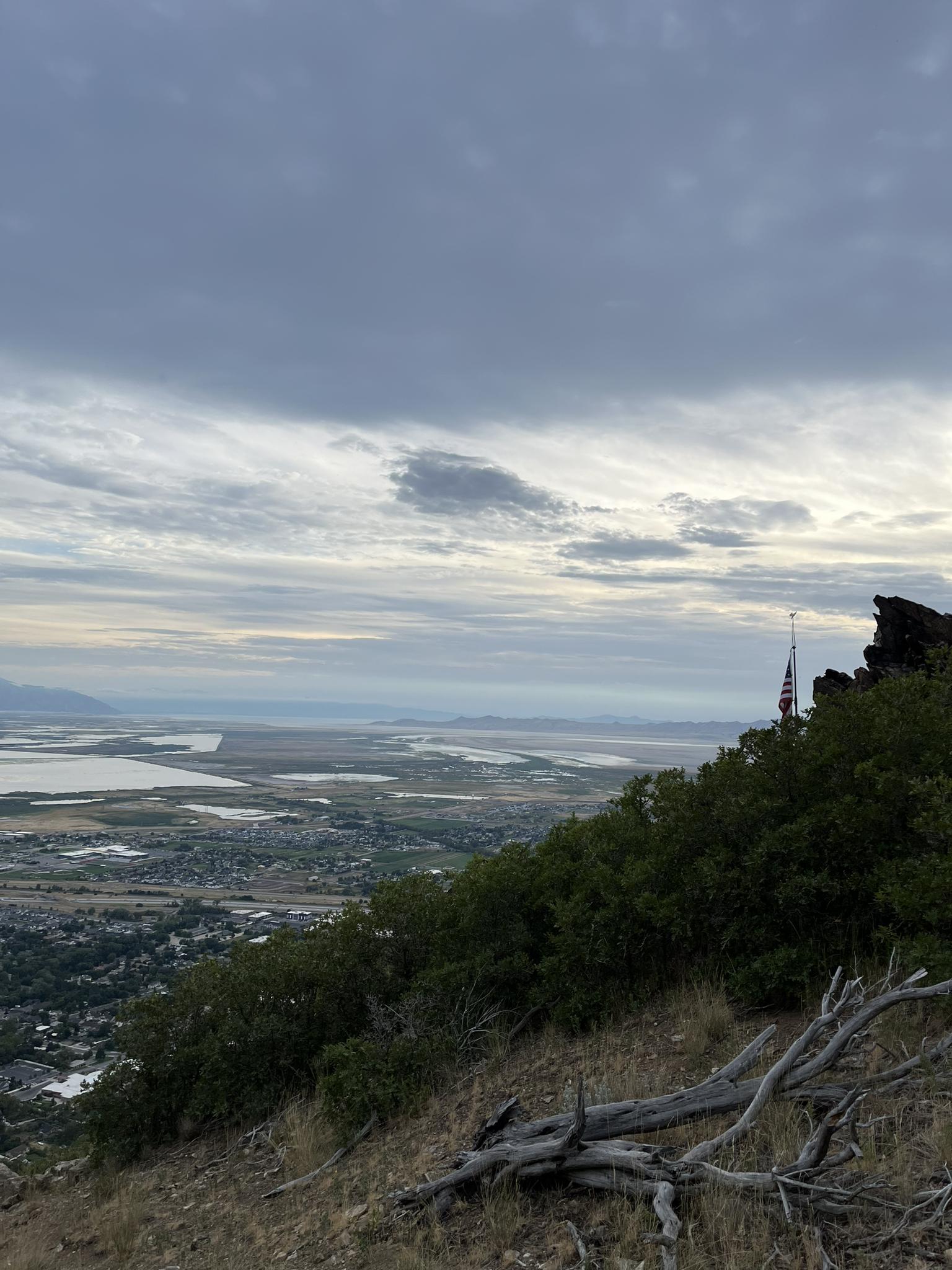 Overcast panoramic view from a rocky hill, showing distant water and land.