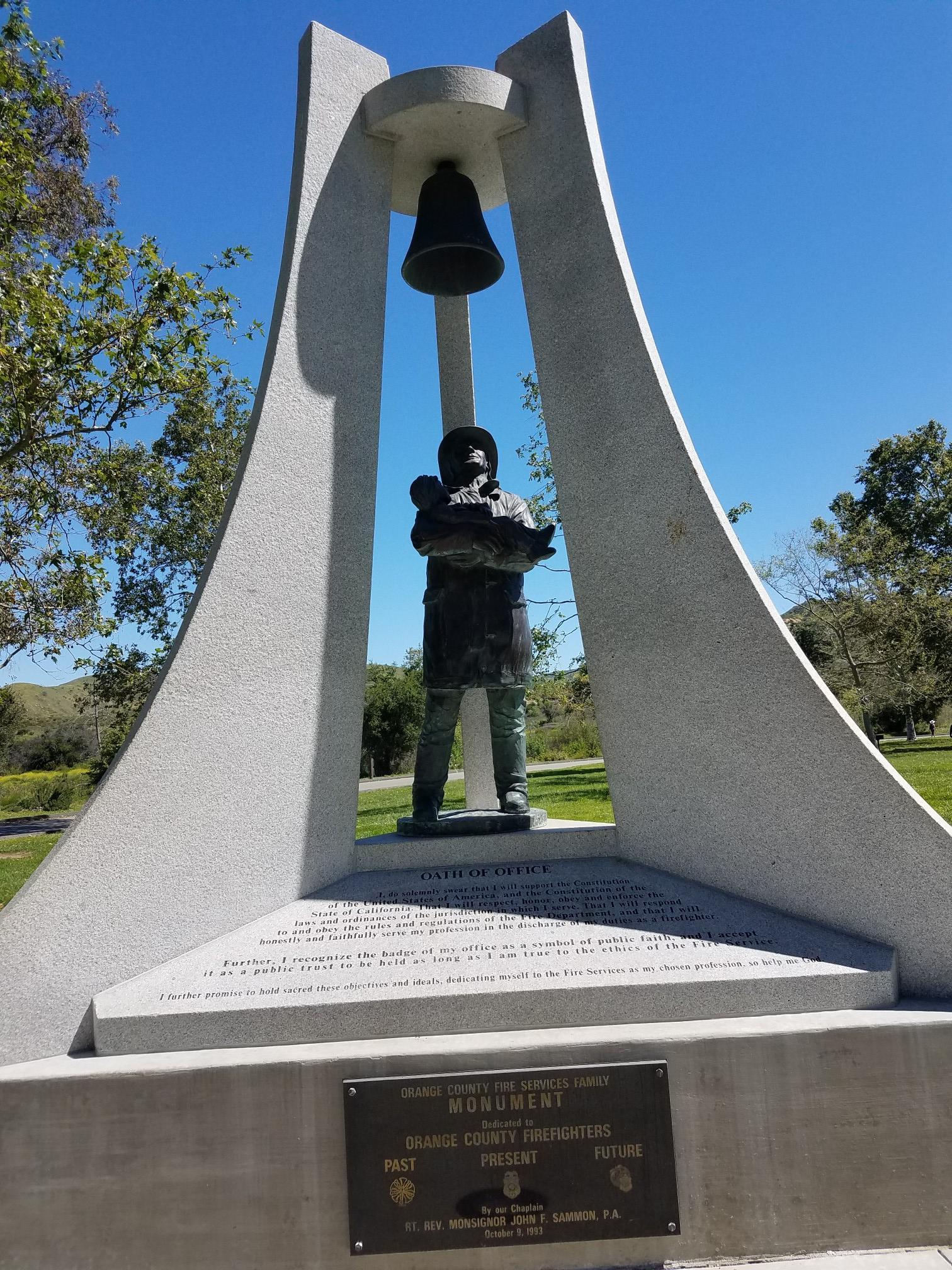 A tall stone monument with a bell and a statue of a person.