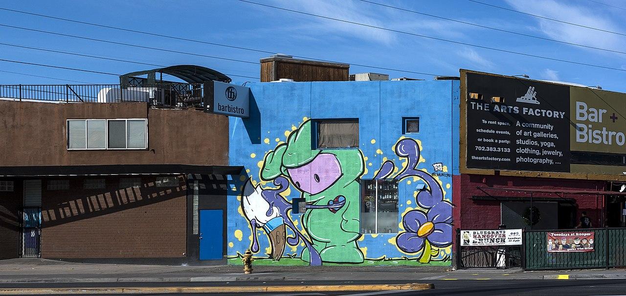 A vibrant blue building with a large cartoon mural under a clear sky.